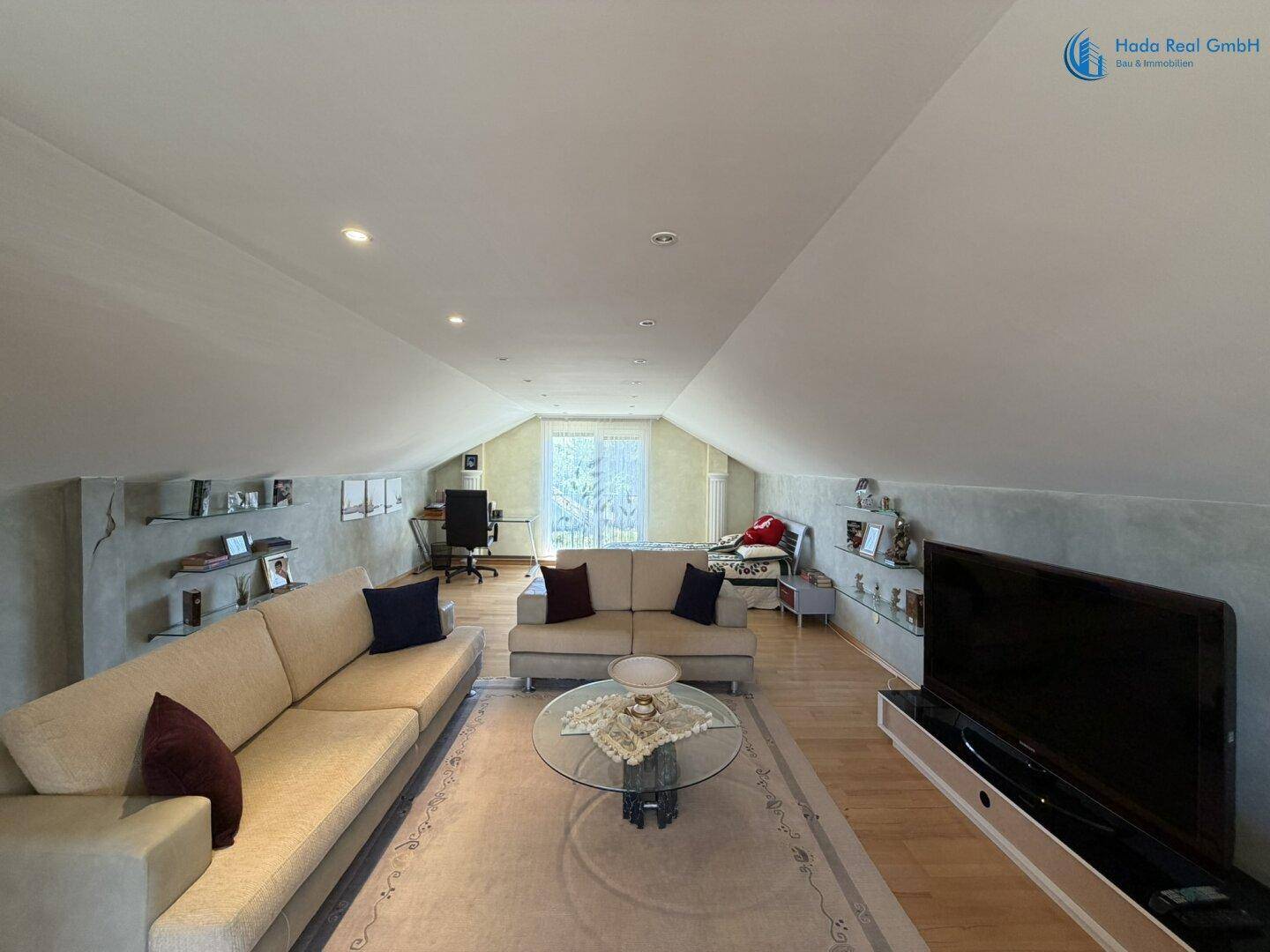 Großzügiges Dachgeschoss-Wohnzimmer mit gemütlichen Sofas, Schreibtischbereich und Dachschrägen.
