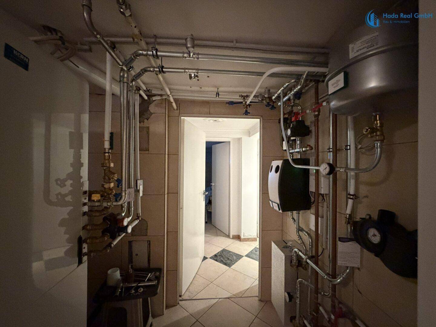 Technikraum mit komplexer Rohrinstallation und einem Warmwasserbereiter für die Hausversorgung.