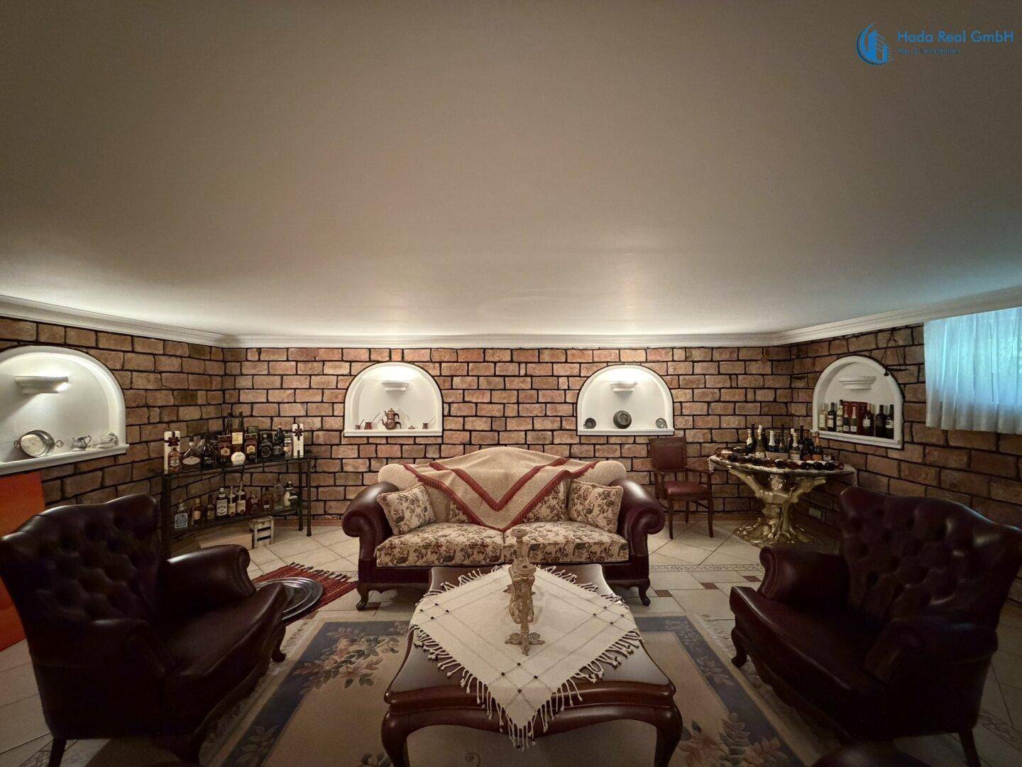 Gemütlicher Wohnbereich im Keller mit Ziegelwänden, bequemen Sofas und einer Hausbar.