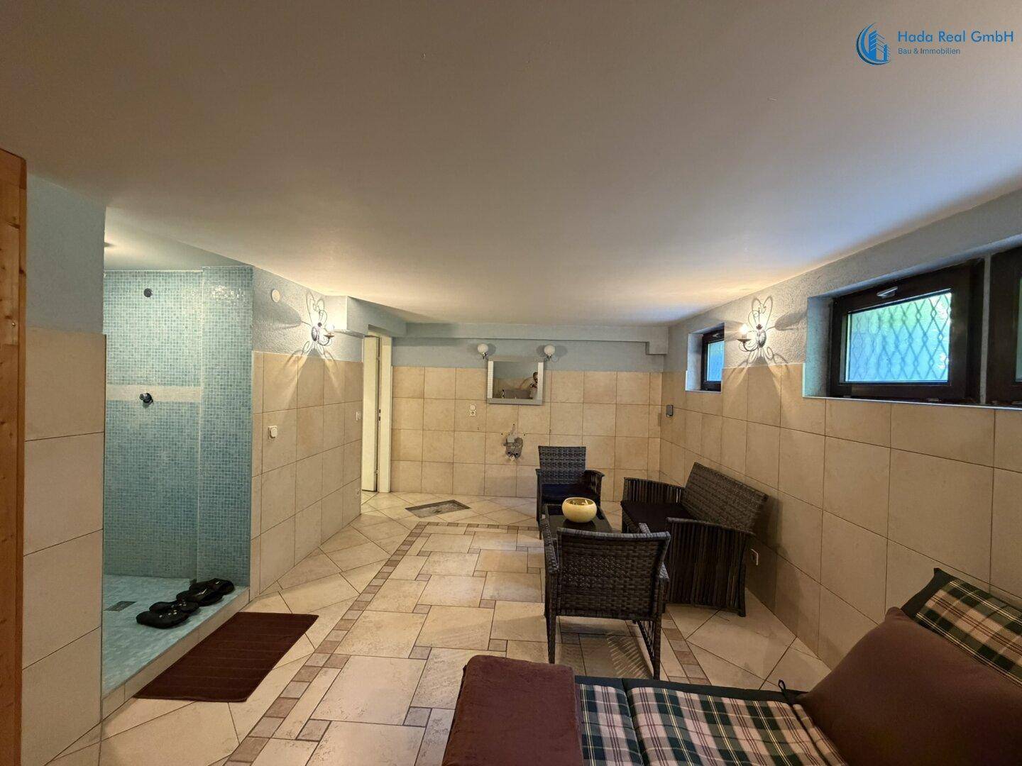 Heller Wellnessbereich mit Fliesenboden, Duschbereich und Fenstern für Tageslicht.