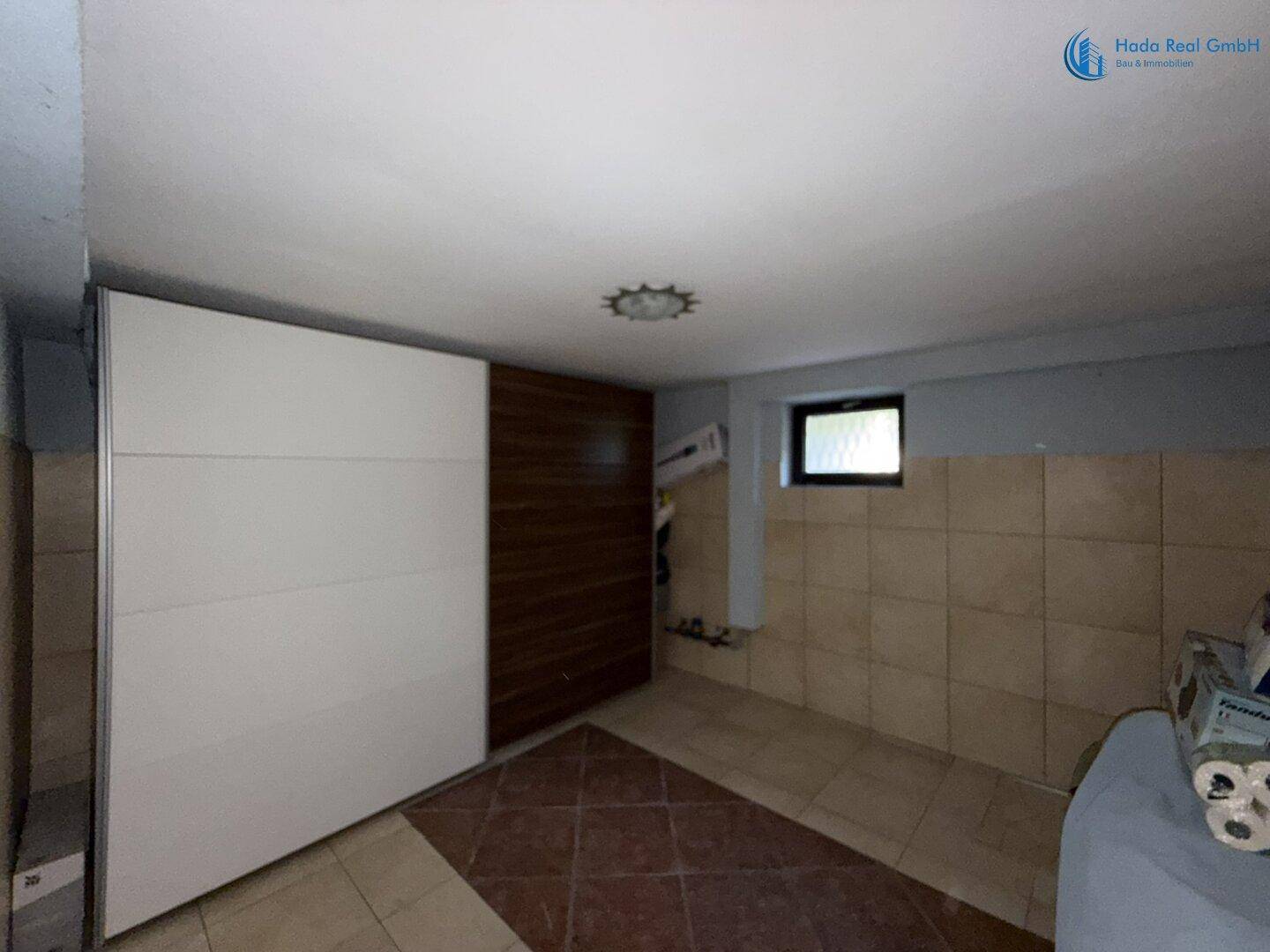 Kellerraum mit Schiebetürenschrank und Fliesenboden, ideal als Abstellraum.