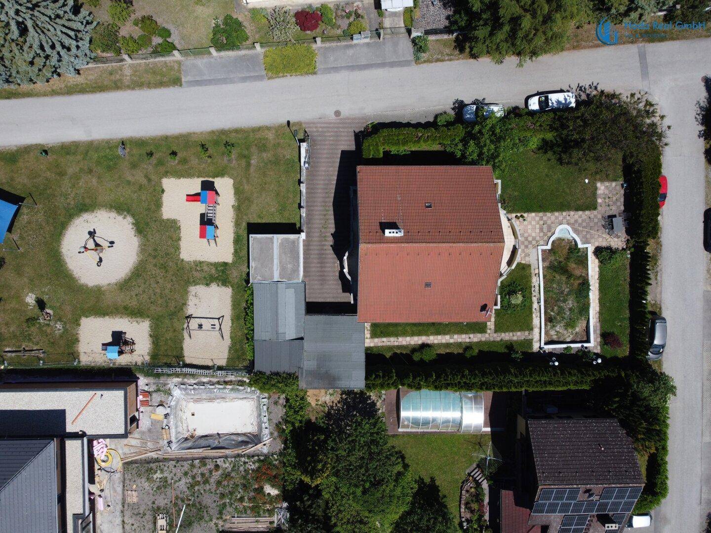 Luftaufnahme des Anwesens mit großem Garten, Spielplatz und Poolbereich.
