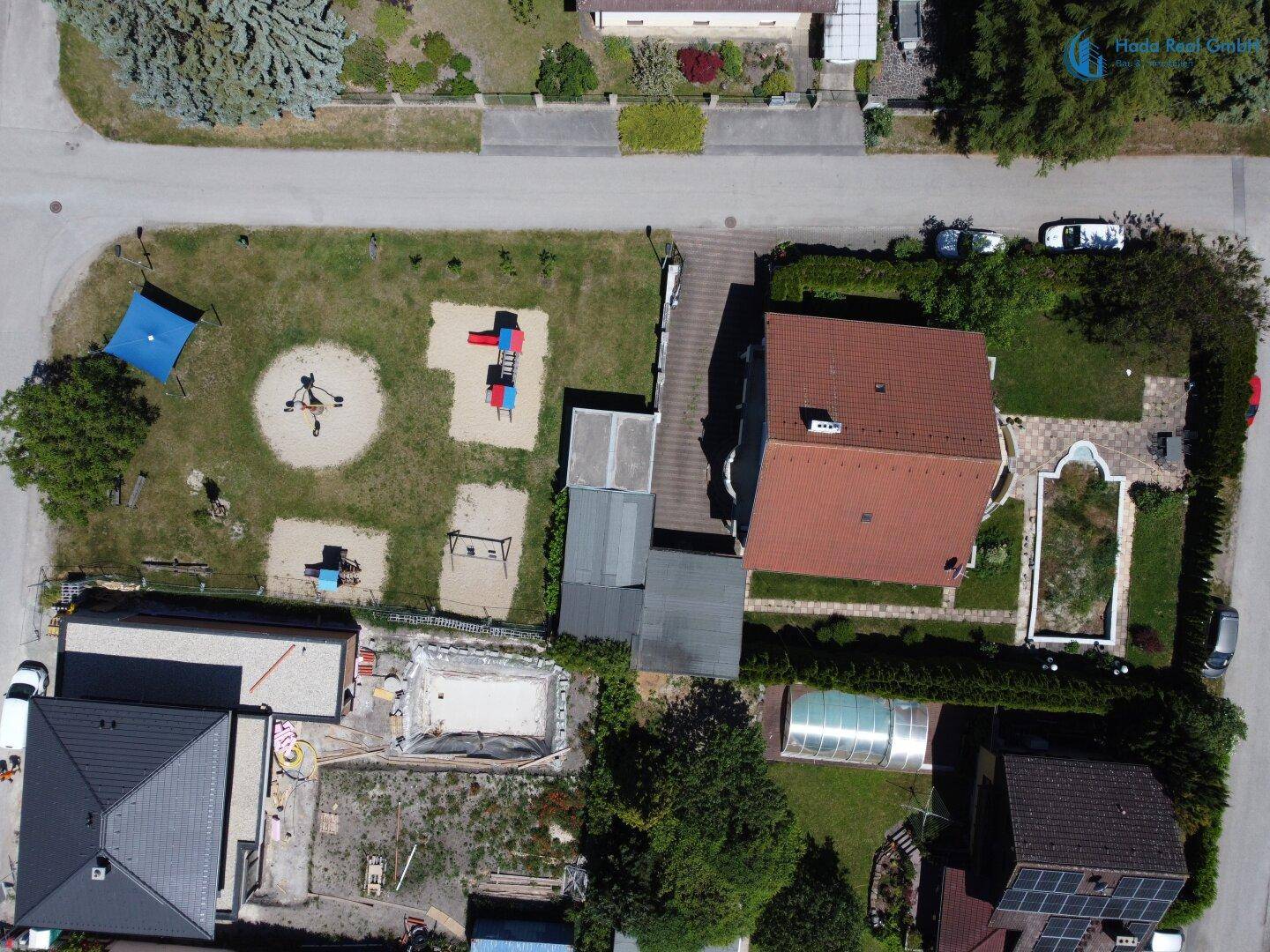 Übersichtliche Luftaufnahme des Grundstücks mit Haus, Garten und Spielplatz.