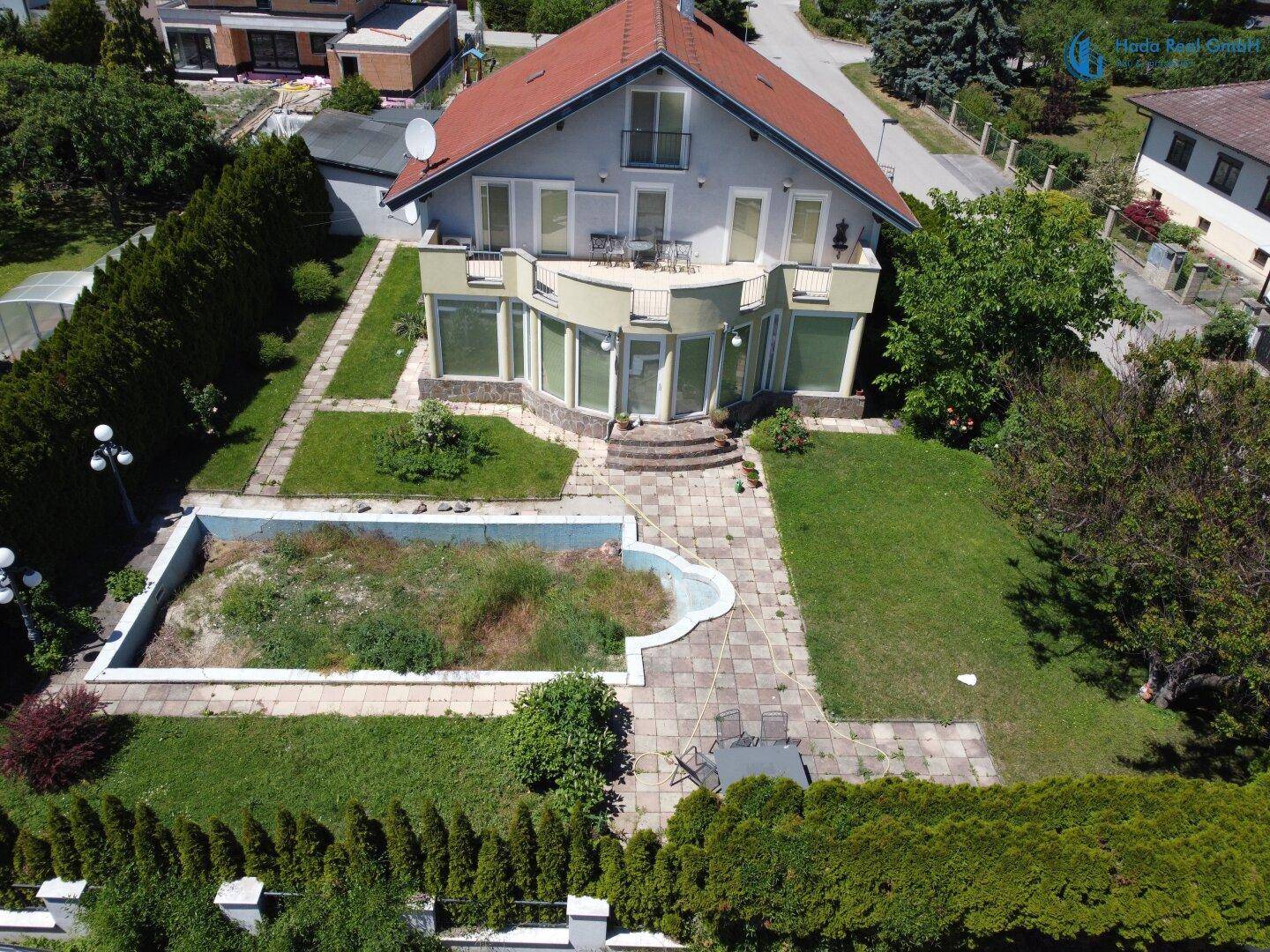 Ansicht des Hauses von oben mit großem Garten, Terrasse und Poolbereich.