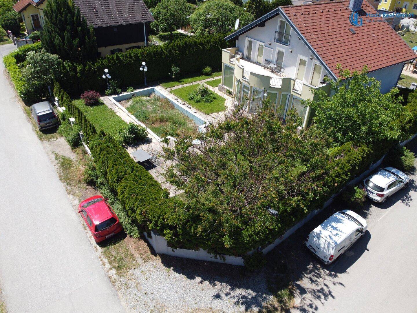 Luftaufnahme des Hauses und des Gartens mit umliegender Nachbarschaft und Straße.