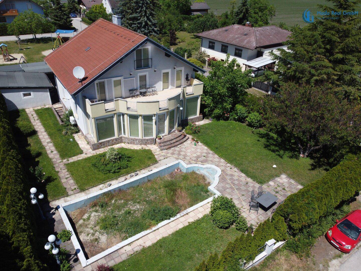 Luftaufnahme des Hauses mit großem Garten, Terrasse und Poolbereich von der Seite.