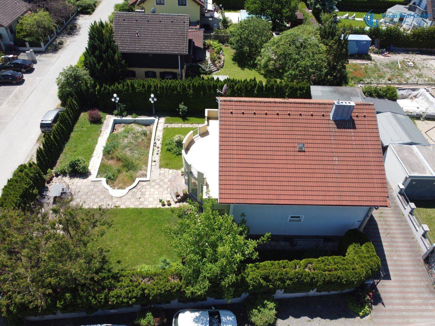 Luftaufnahme des Hauses mit rotem Ziegeldach, Garten und angrenzendem Carport.