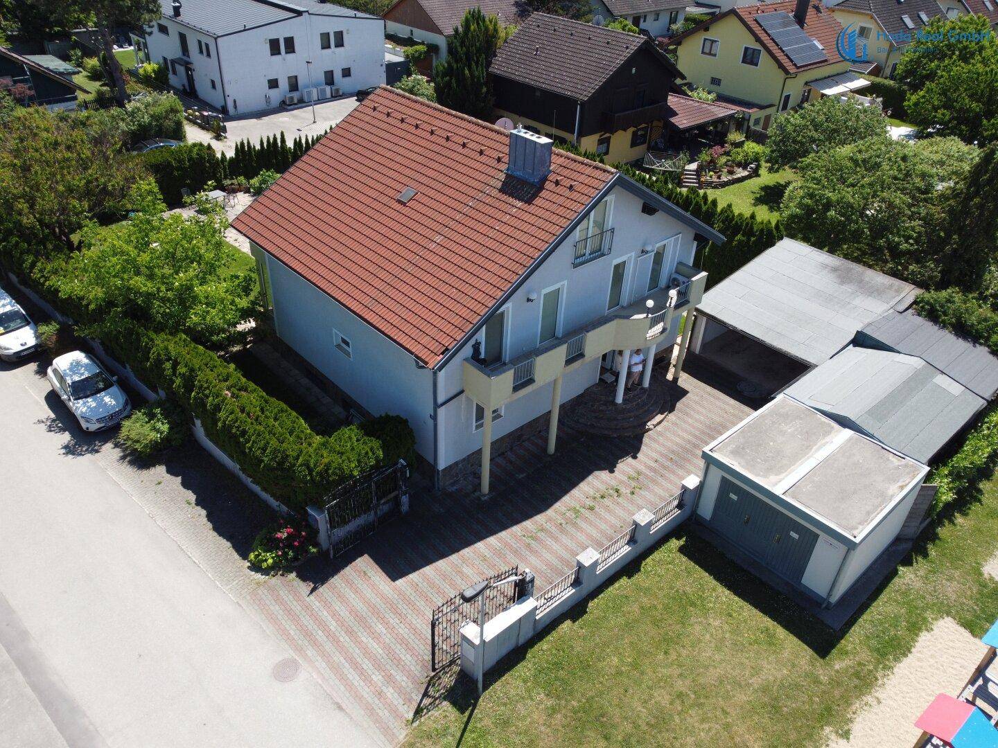 Luftaufnahme des Hauses mit rotem Ziegeldach, Balkonen und Carport.