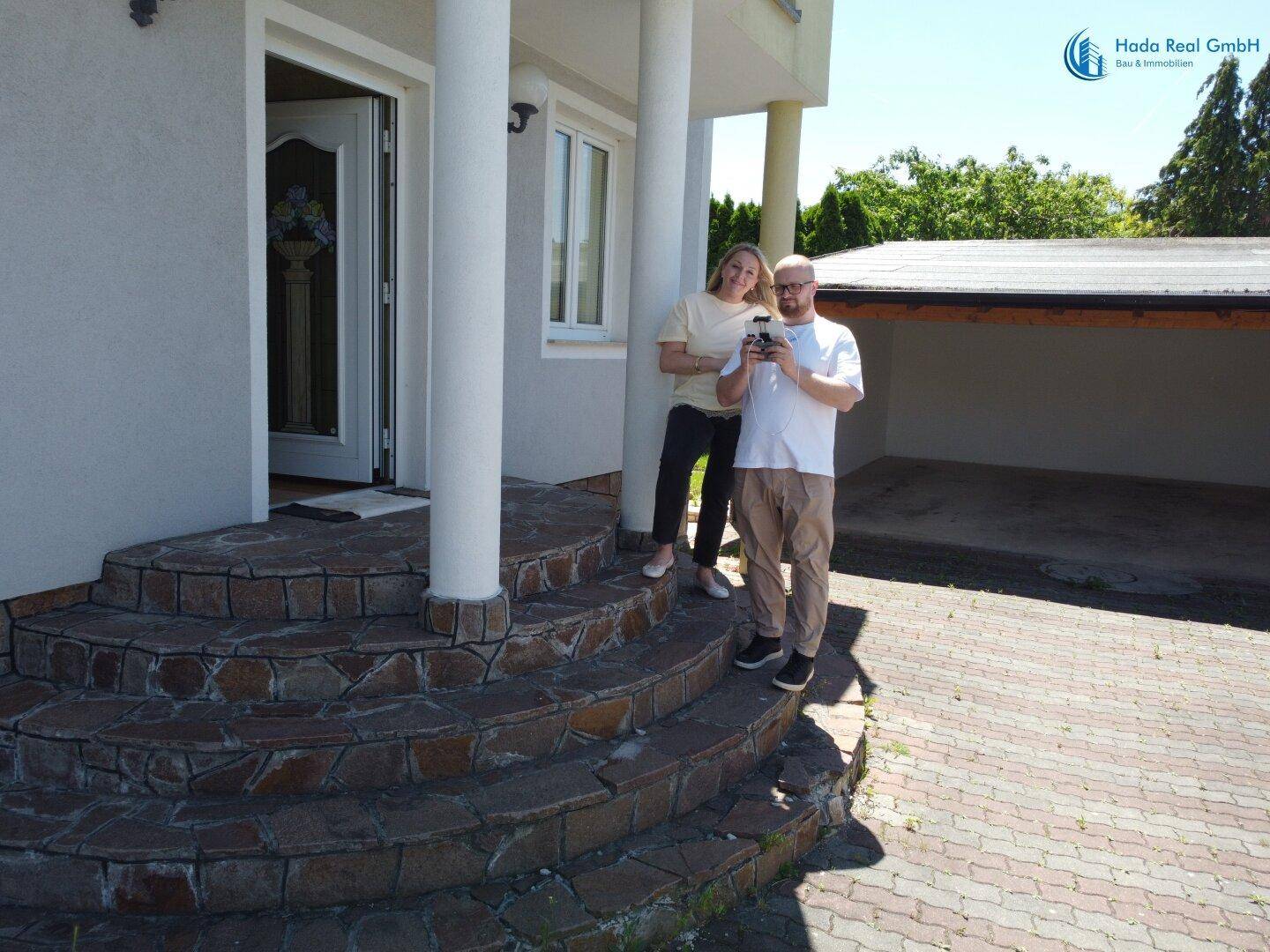 Eingangsbereich des Hauses mit geschwungener Steintreppe und Säulen.