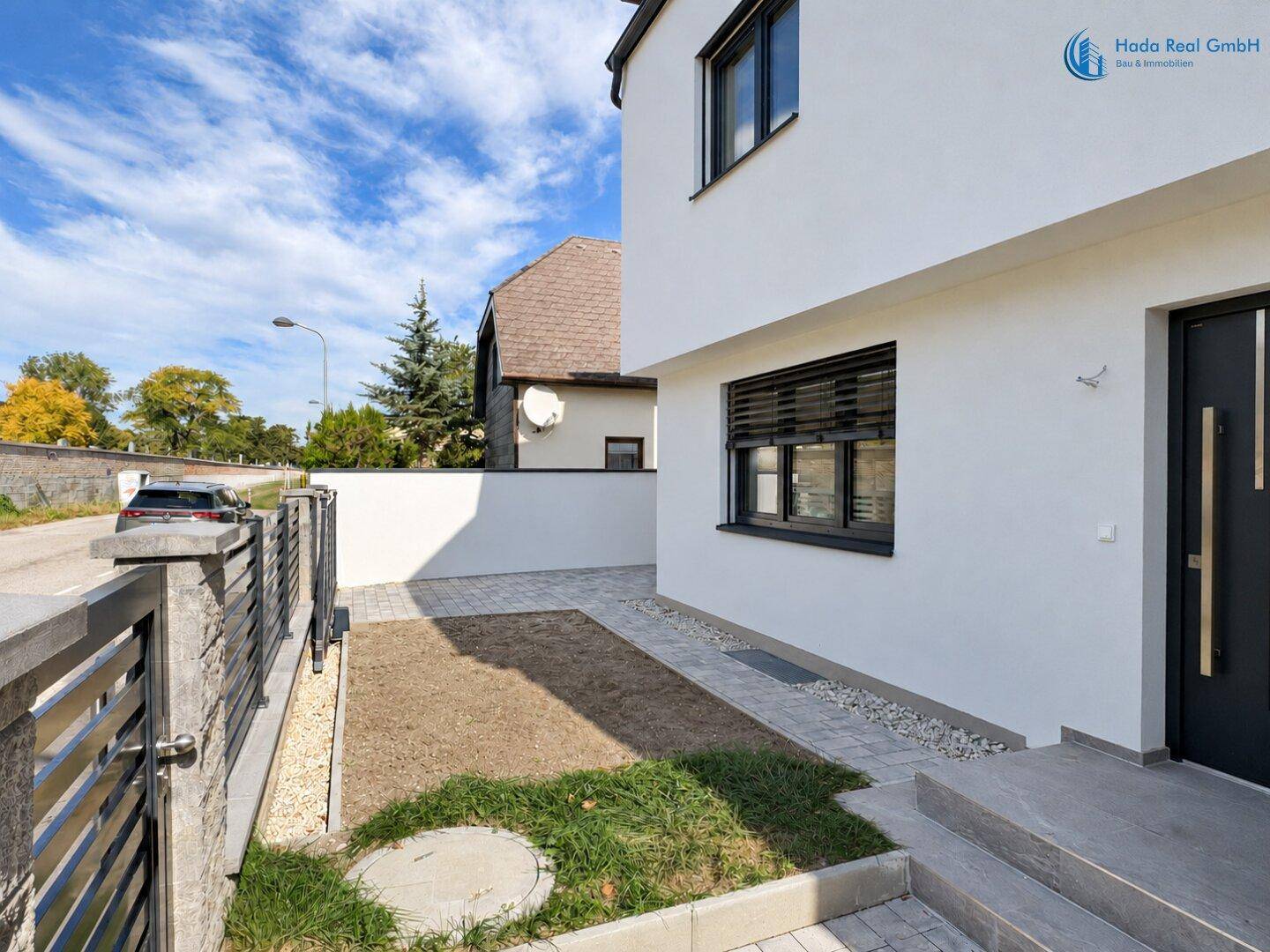 Vorderseite des Hauses mit kleinem Gartenbereich, Zaun und gepflastertem Zugang.