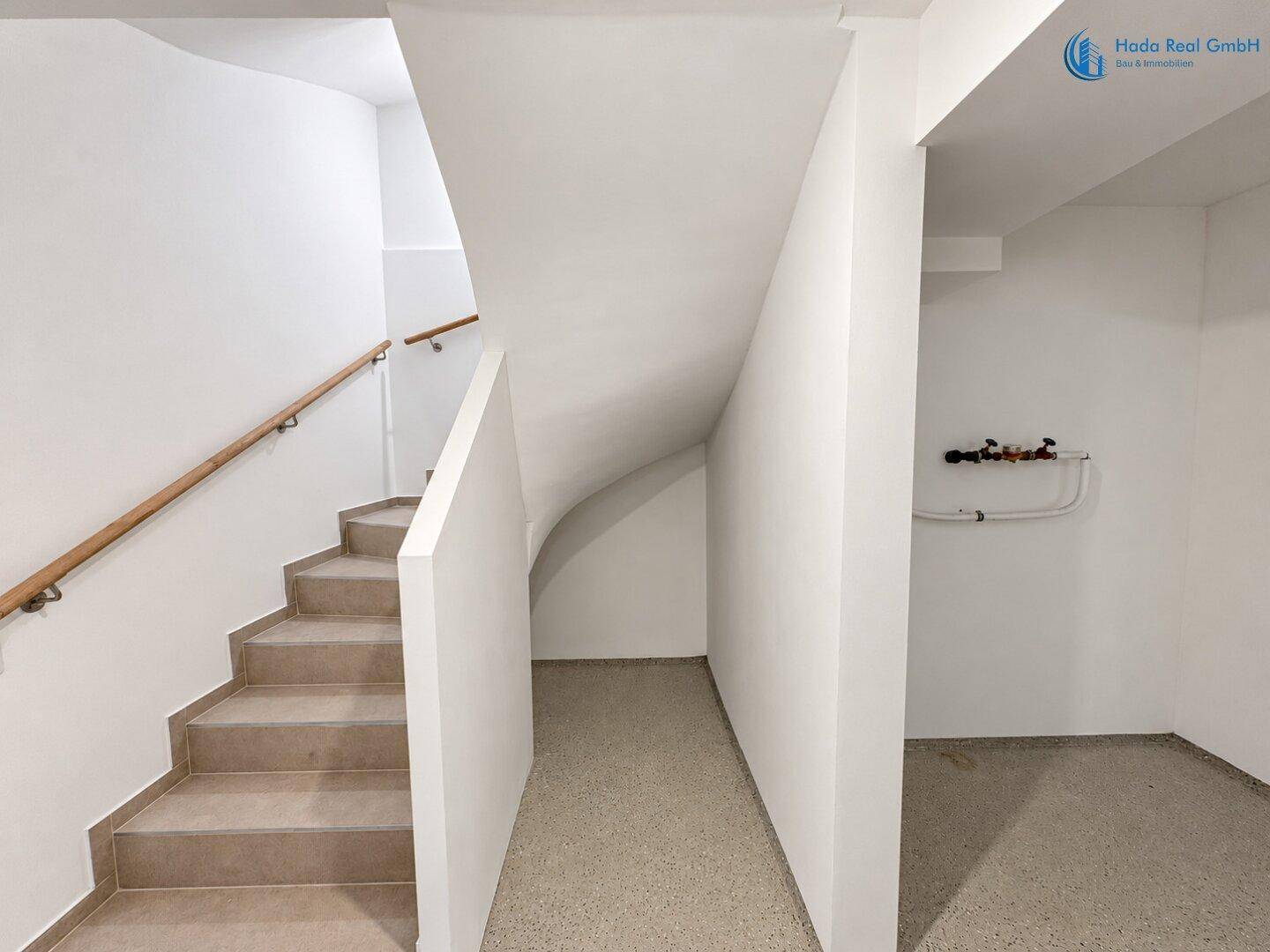 Treppenabgang in den Keller mit robustem Boden und sichtbaren Leitungen an der Wand.