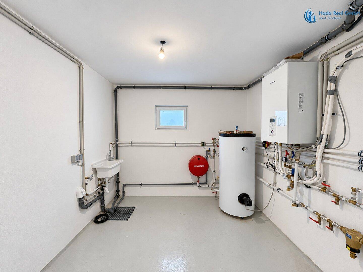 Technikraum im Keller mit Heizungsanlage, Warmwasserspeicher und Waschbecken.