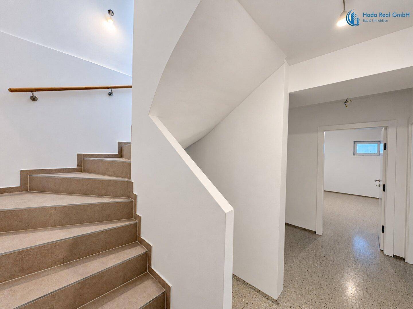 Heller Flur mit Steintreppe und Terrazzoboden, der zu weiteren Räumen führt.