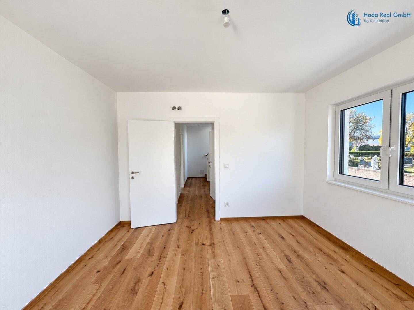 Helles Zimmer mit Holzboden und Fenster, ideal als Schlaf- oder Arbeitszimmer nutzbar.