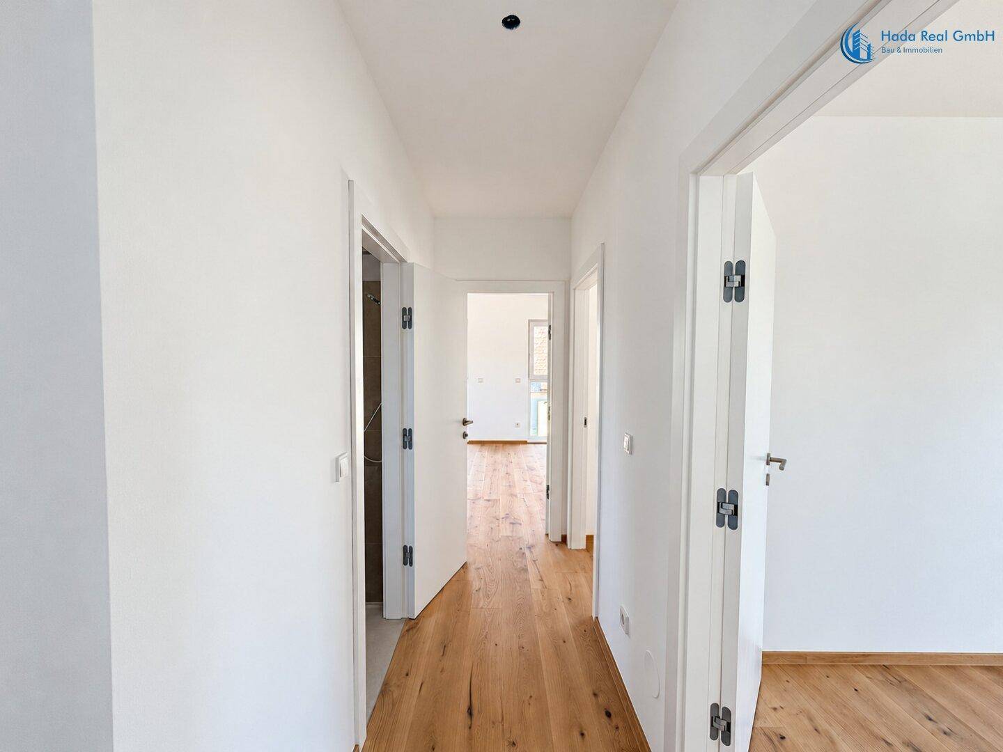Heller Flur mit Holzboden und Türen, die zu den verschiedenen Wohnbereichen führen.
