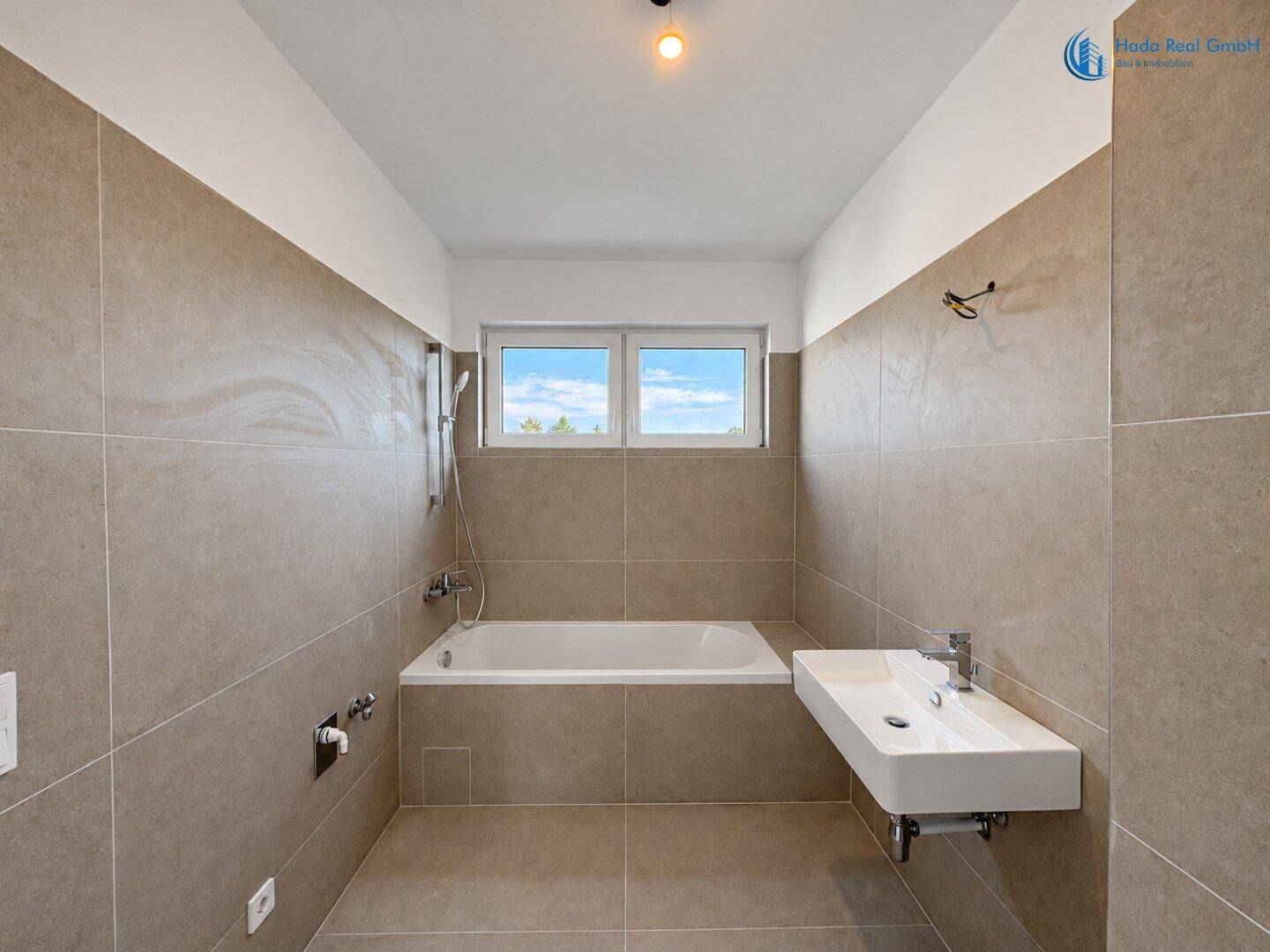 Modernes Badezimmer mit Badewanne, Waschbecken und Fenster für natürliche Belüftung.