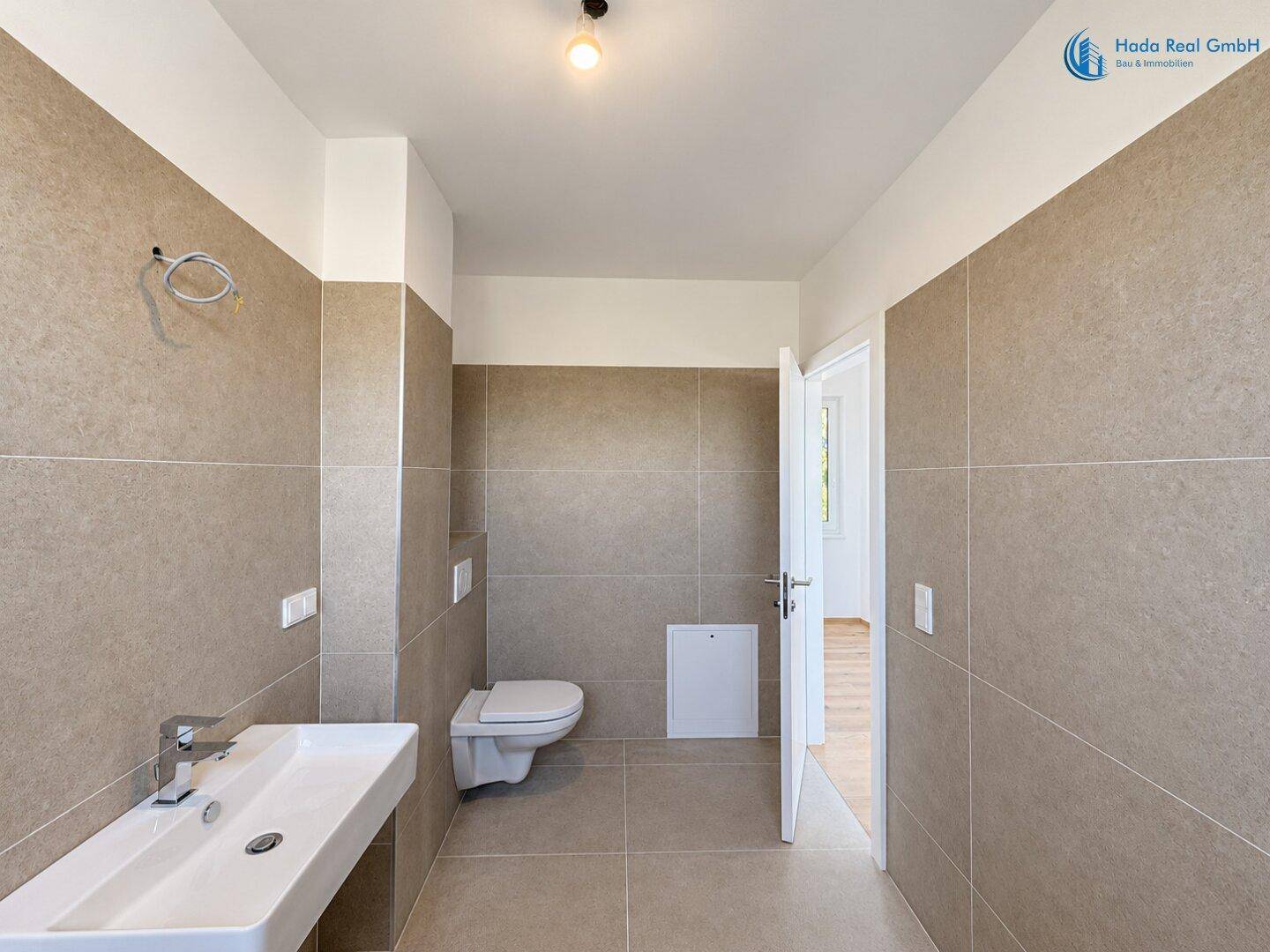 Modernes Badezimmer mit Wand-WC, Waschbecken und Fliesenboden.