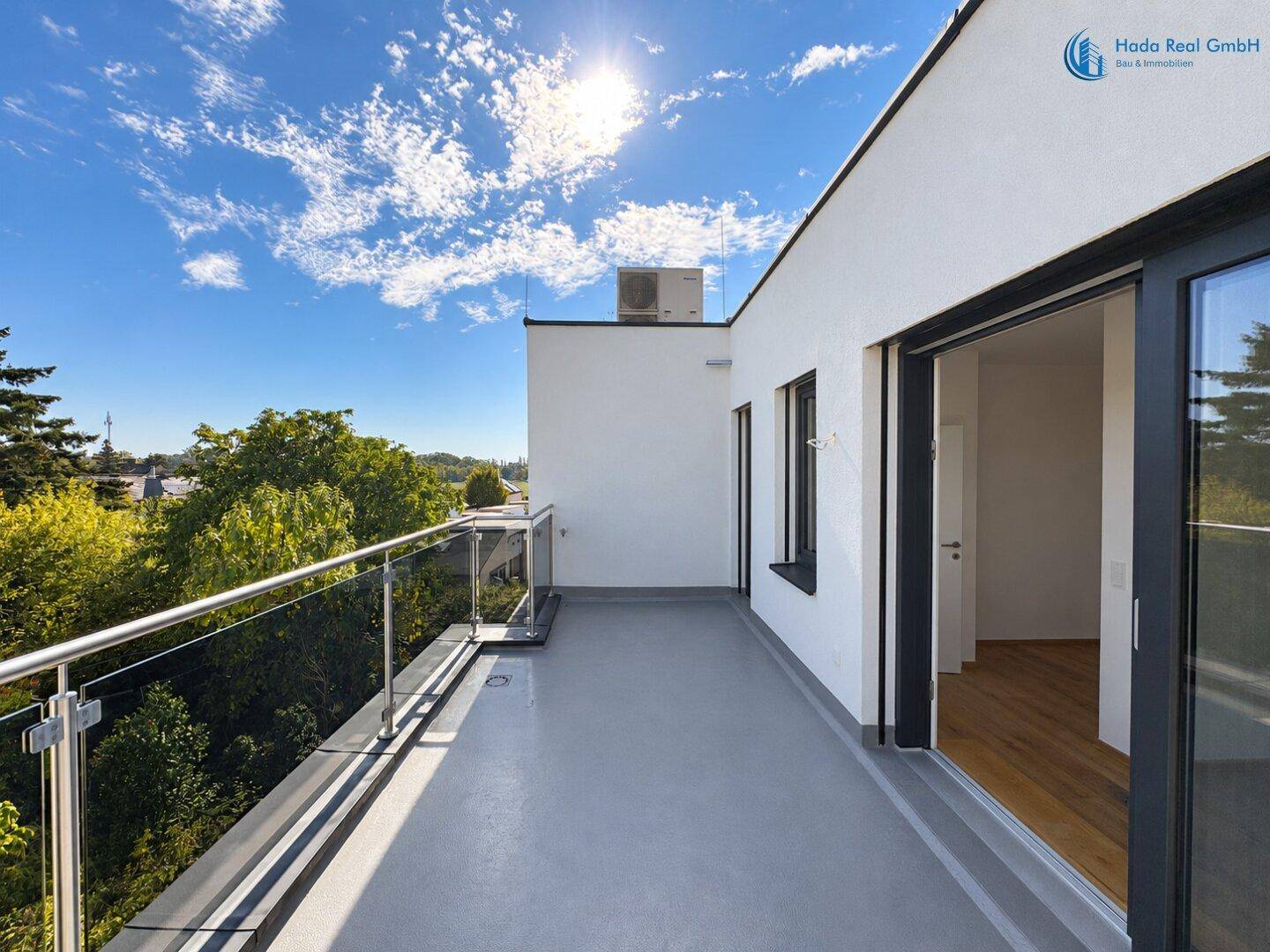 Großer Balkon mit Glasgeländer und weitem Blick über die Umgebung.