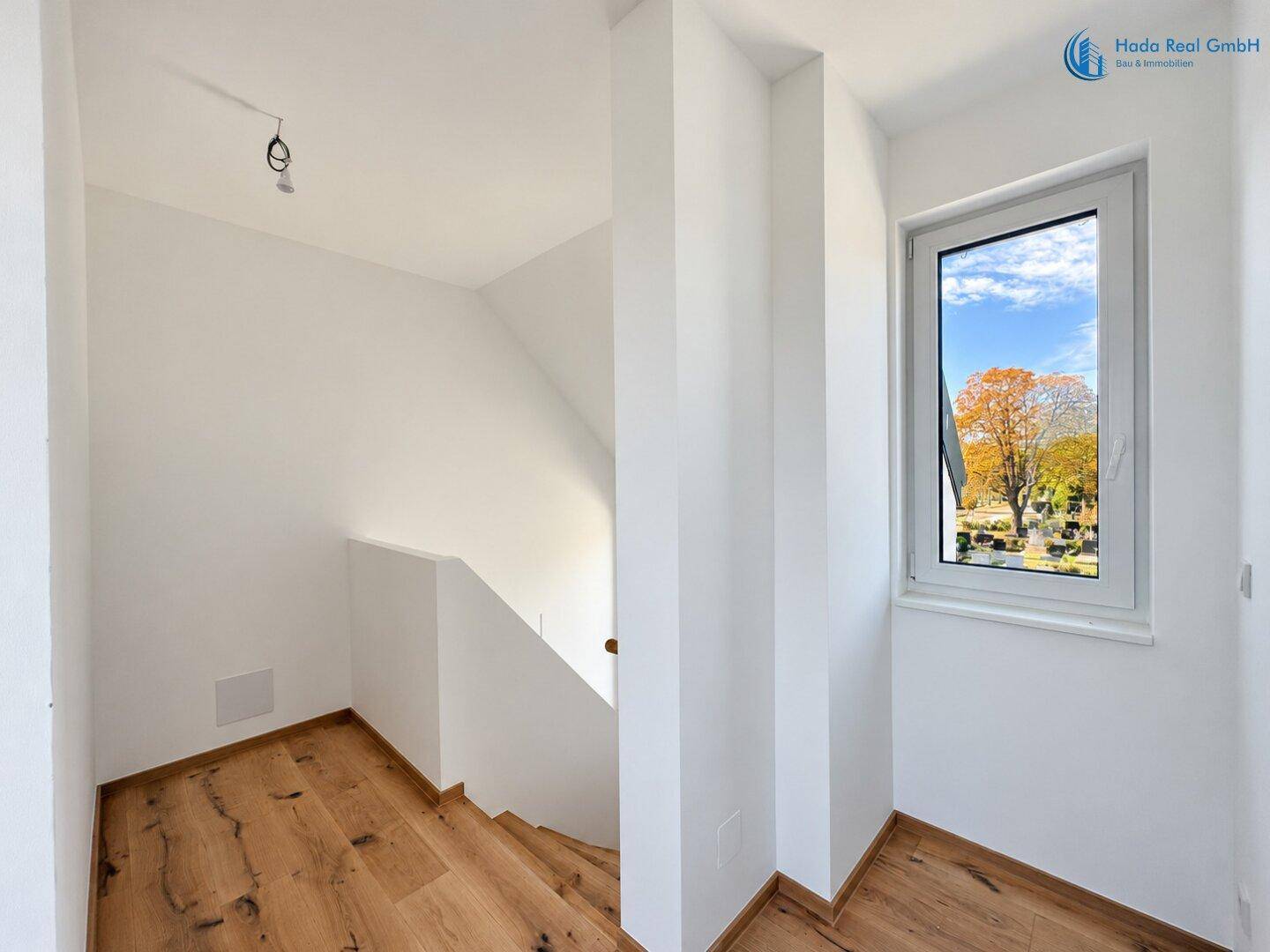 Heller Treppenabsatz mit großem Fenster, das viel Tageslicht hereinlässt.