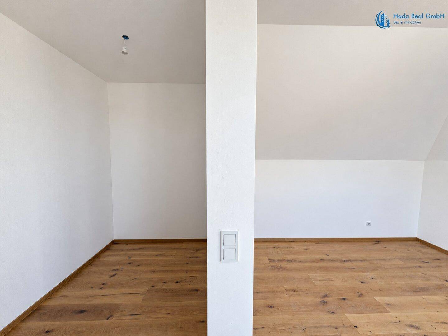 Geräumiger, heller Dachbodenraum mit neuem Holzfußboden und weißen Wänden, bereit zum Ausbau.