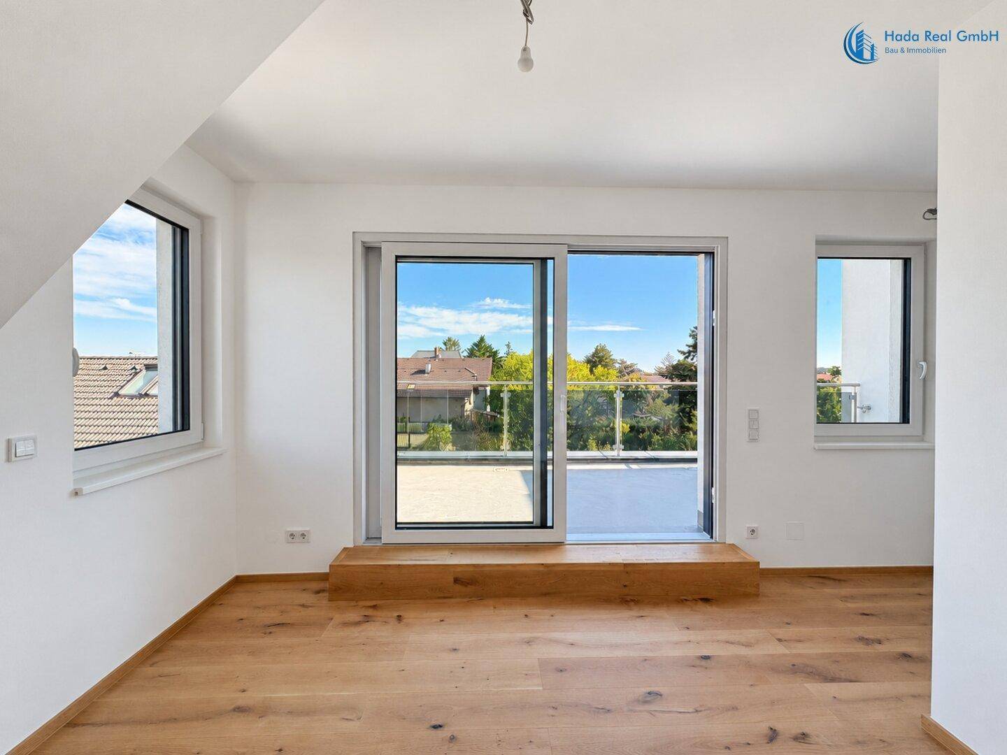 Geräumiger, heller Raum mit Holzboden, großen Schiebetüren zur Terrasse und viel Tageslicht.