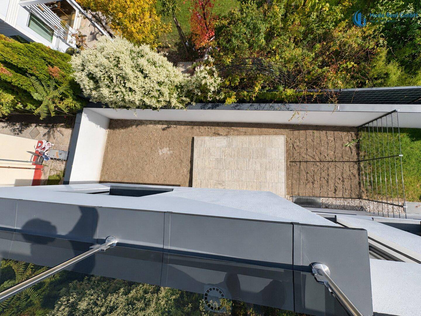 Blick von oben auf einen kleinen Gartenbereich mit Kies und einer gepflasterten Fläche.