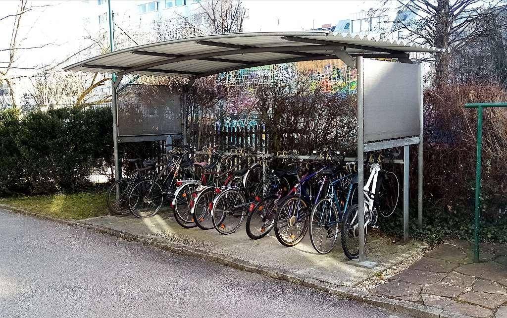 Überdachter Fahrradabstellplatz mit zahlreichen Fahrrädern, bietet Schutz vor Witterungseinflüssen.