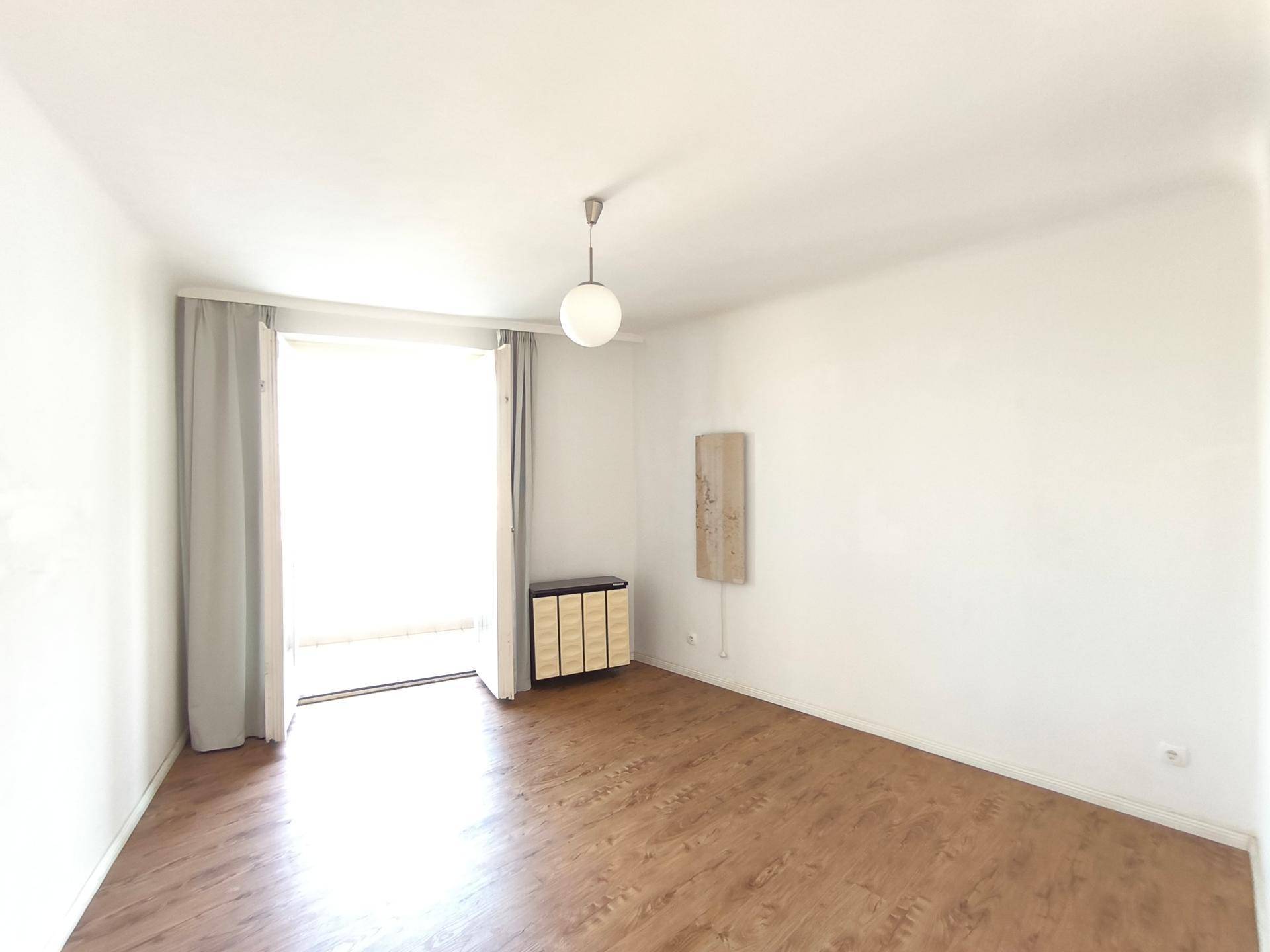 Heller, leerer Raum mit Laminatboden und Zugang zu einem Balkon, ideal als Wohn- oder Schlafzimmer.