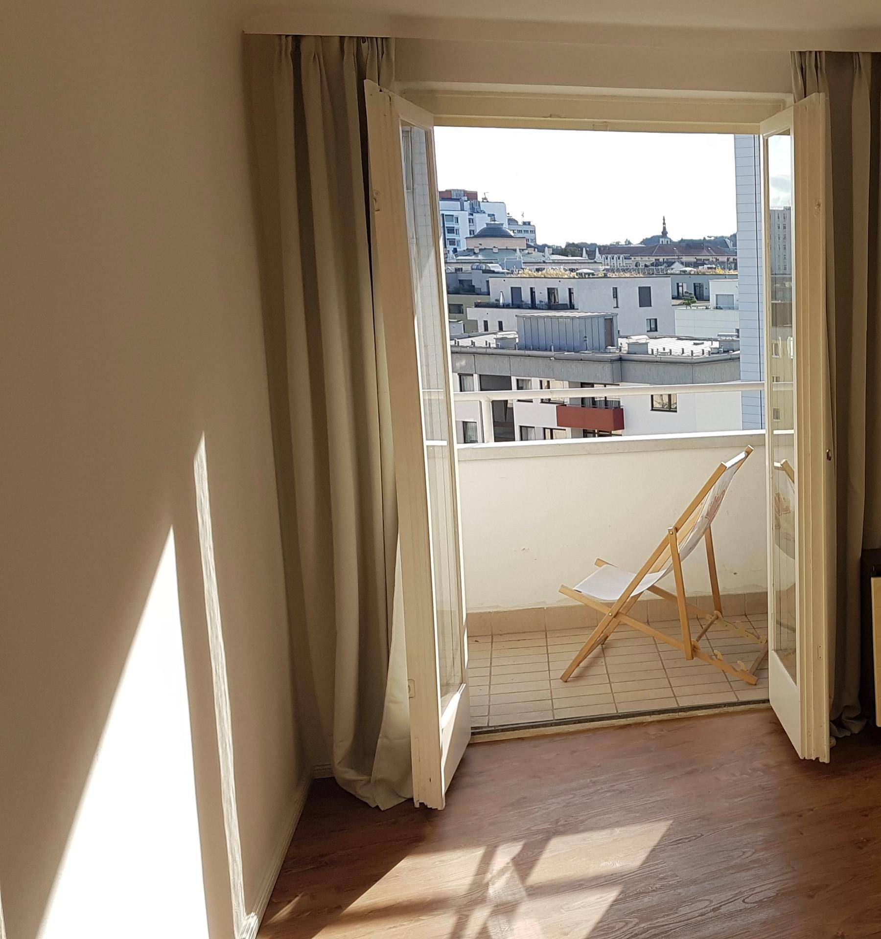 Kleiner Balkon mit einem Stuhl und Blick über die Dächer der Stadt, ideal zum Entspannen.