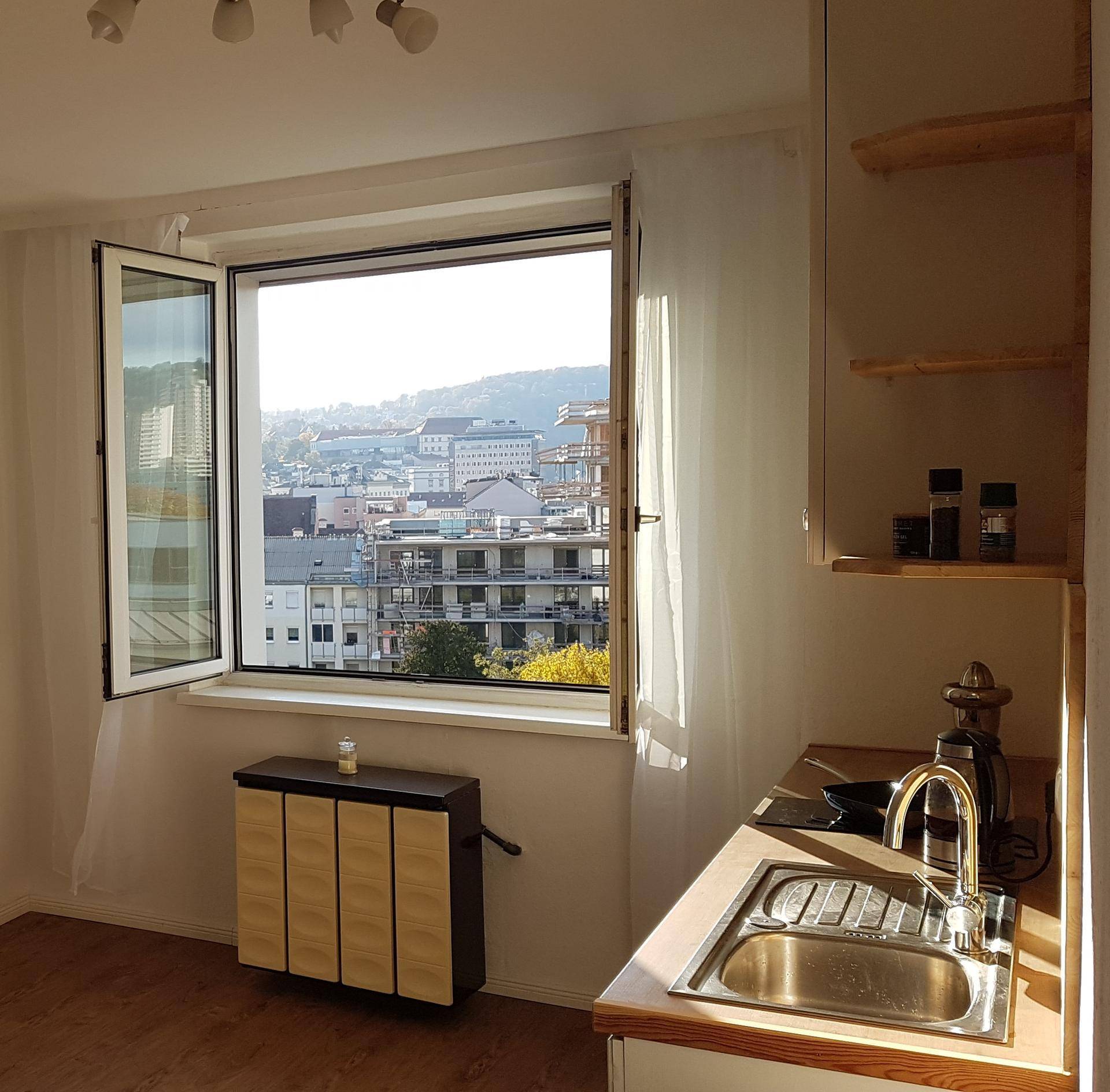 Kleine Küche mit Spülbecken und Fenster, das einen Blick auf die Stadt und die umliegenden Hügel bietet.