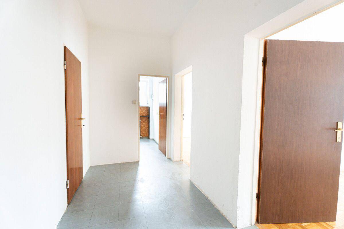 Heller Flur mit Fliesenboden und mehreren Holztüren, der zu verschiedenen Räumen führt.