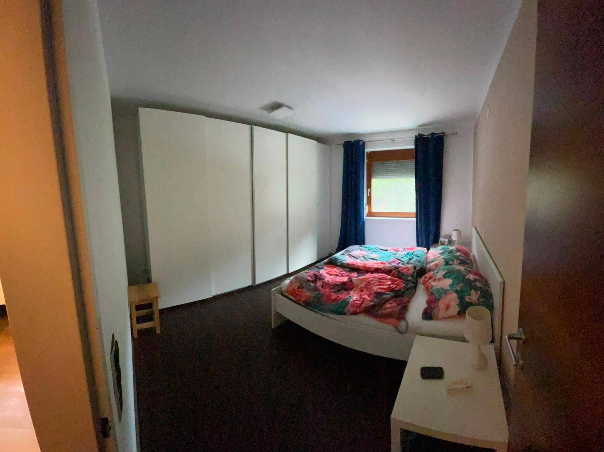 Geräumiges Schlafzimmer mit großen Einbauschränken, Laminatboden und Blick ins Grüne.