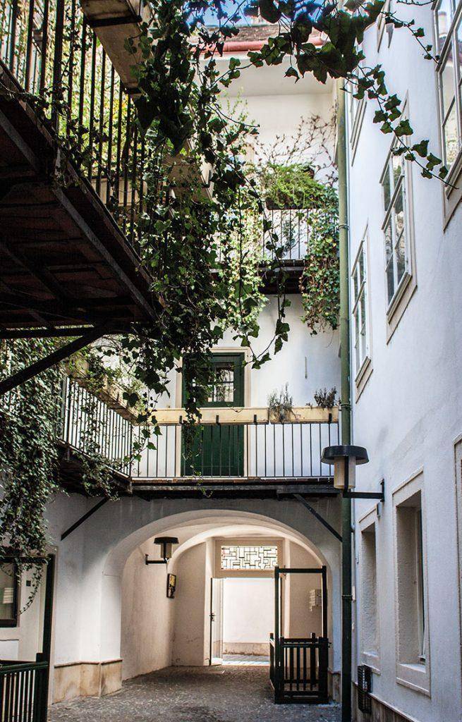 Historischer Innenhof mit Arkadengang und begrünten Balkonen, die eine charmante Atmosphäre schaffen.