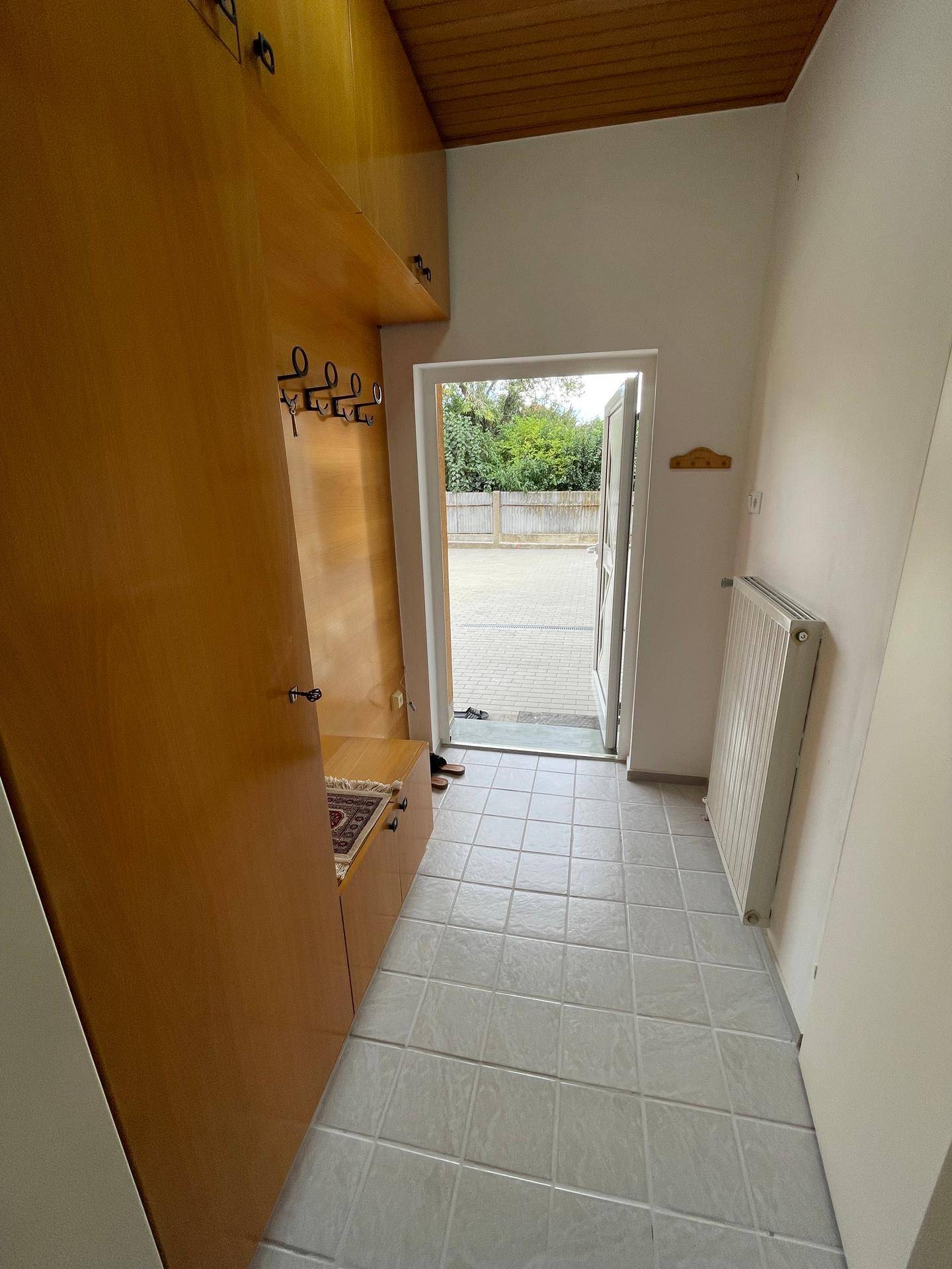 Eingangsbereich mit Garderobe, Fliesenboden und Zugang zum Außenbereich, hell und funktional gestaltet.