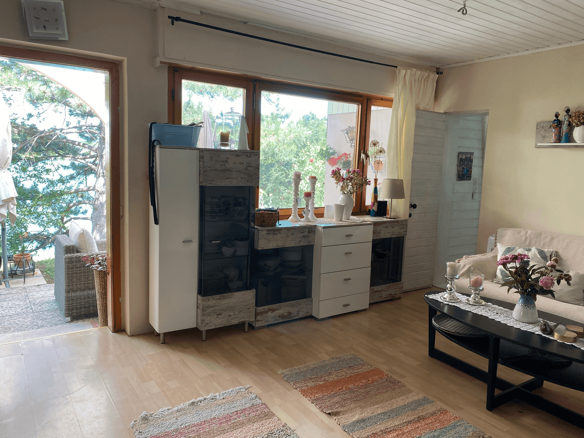 Wohnzimmer mit großen Fenstern und Zugang zur Terrasse, bietet viel Tageslicht und Seeblick.