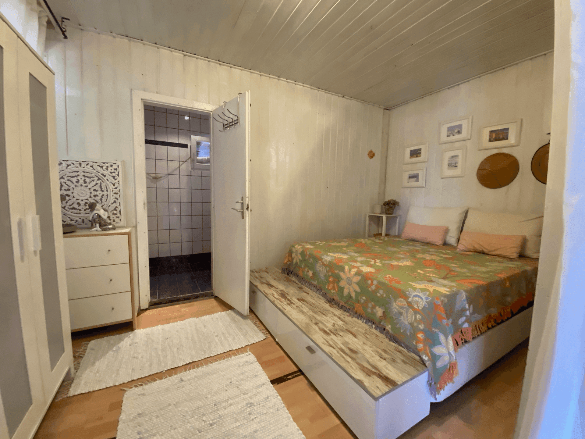 Schlafzimmer mit Holzbett und direktem Zugang zu einem gefliesten Badezimmer.