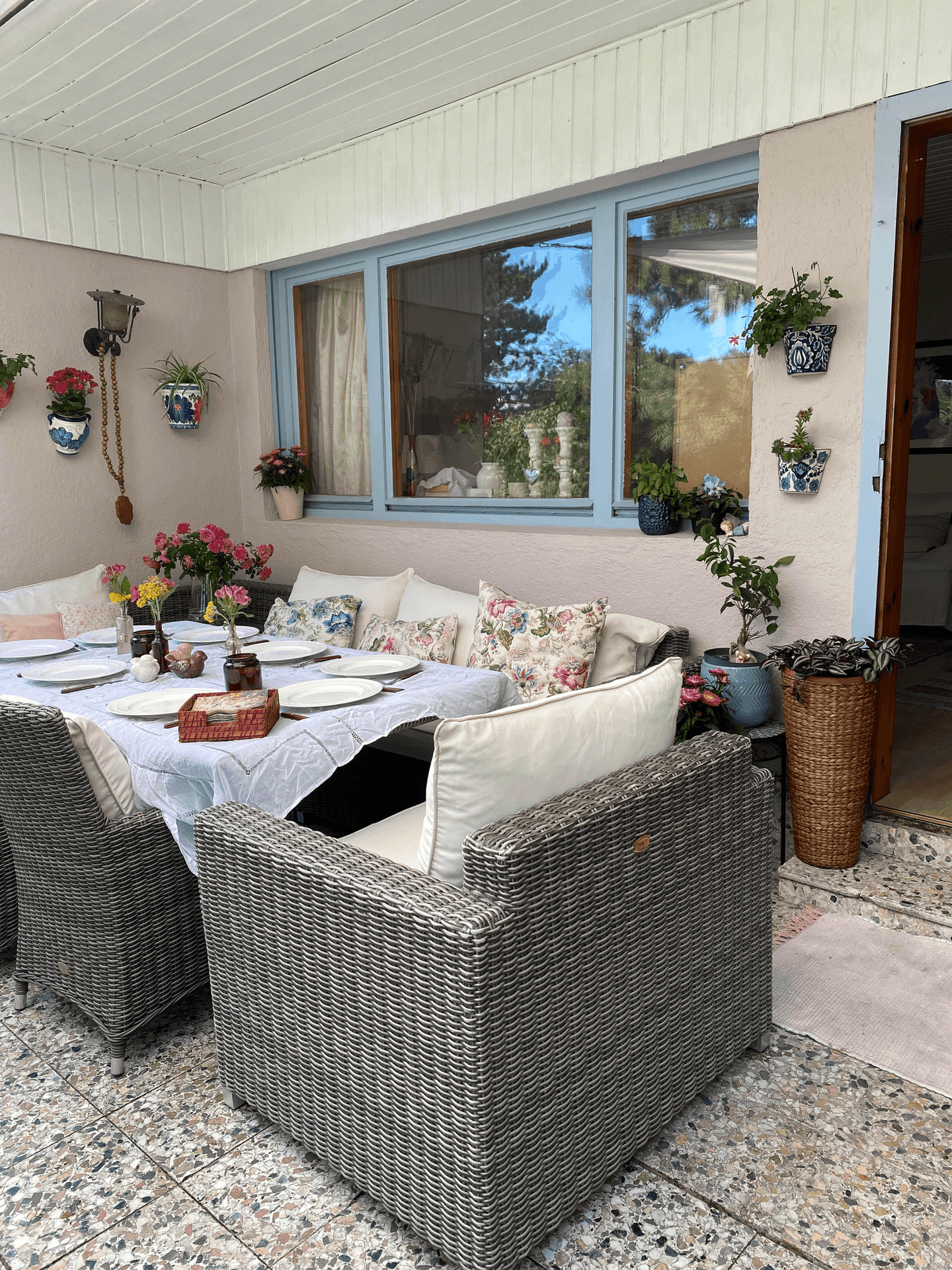 Überdachte Terrasse mit großem Esstisch und bequemen Korbsesseln, ideal für Mahlzeiten im Freien.