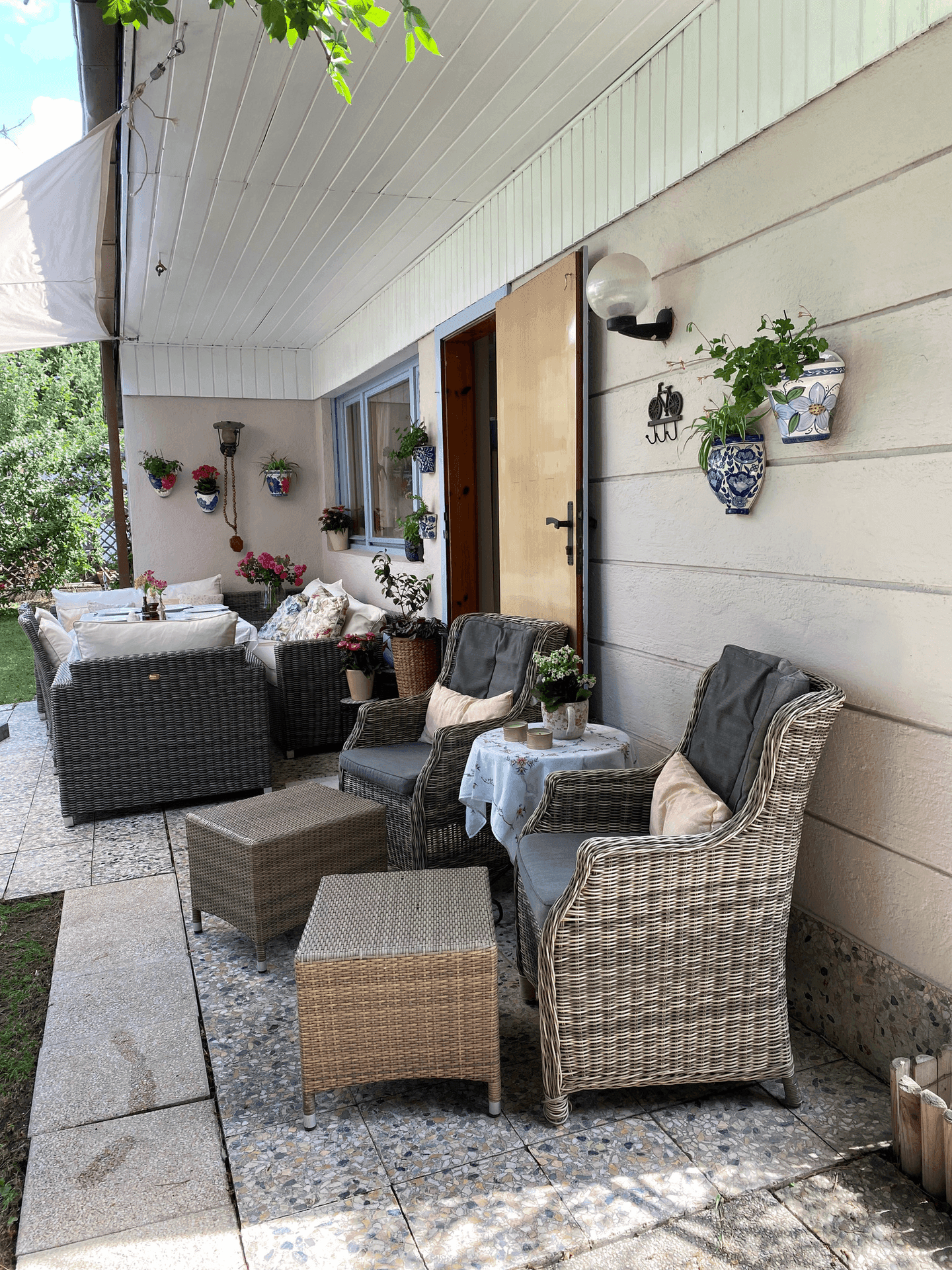 Gemütliche überdachte Terrasse mit Lounge-Möbeln und dekorativen Wandtöpfen, ideal zum Entspannen.