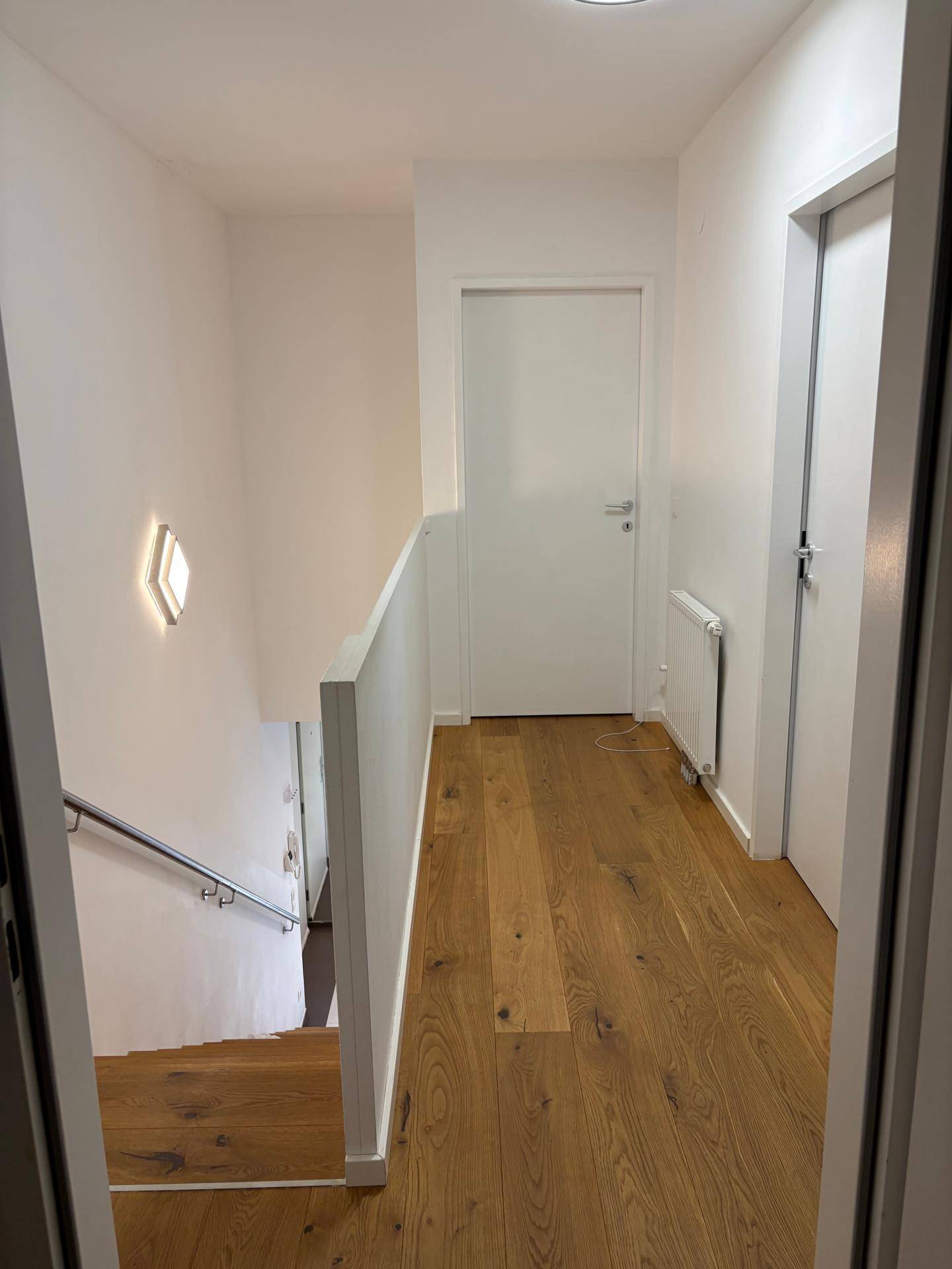 Heller Flur im Obergeschoss mit Holzboden und Zugang zu den Zimmern.