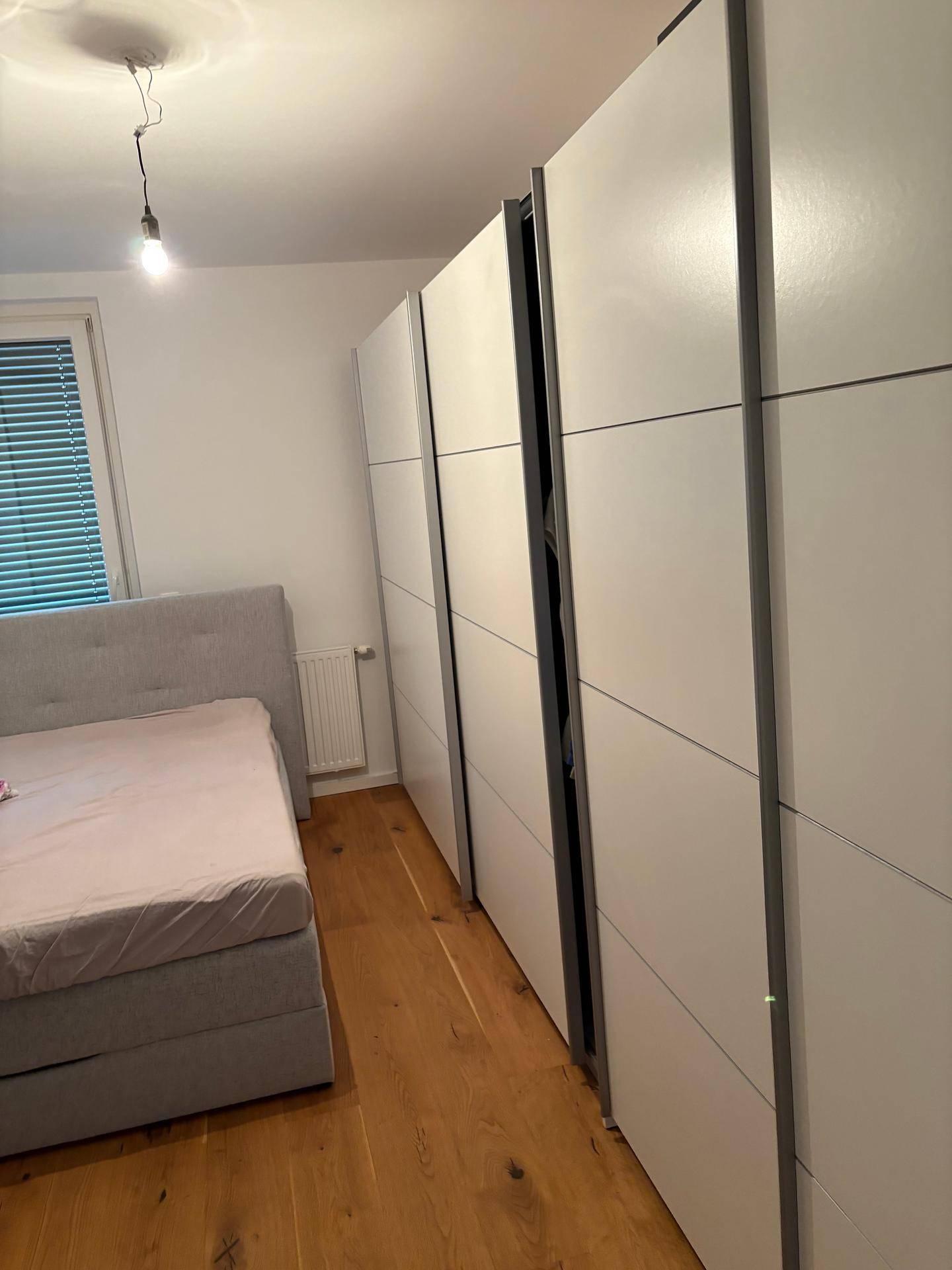 Schlafzimmer mit Holzboden und einer Reihe von weißen Einbauschränken.