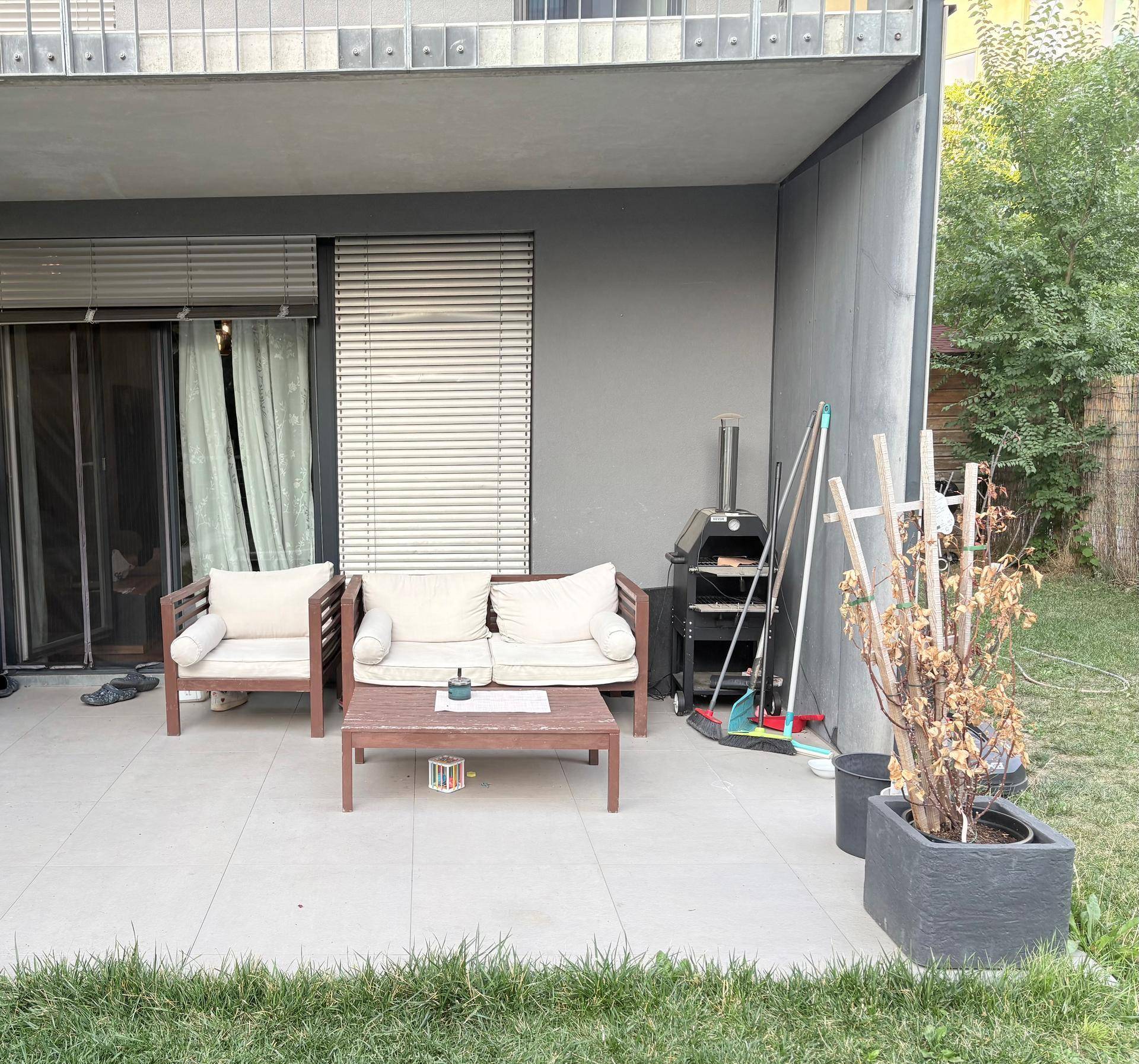 Gemütliche Terrasse mit modernen Gartenmöbeln, Grillbereich und direktem Zugang zum Rasen.
