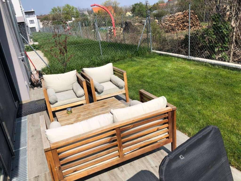 Gemütlicher Gartenbereich mit Holzmöbeln und Rasenfläche, ideal zum Entspannen im Freien.