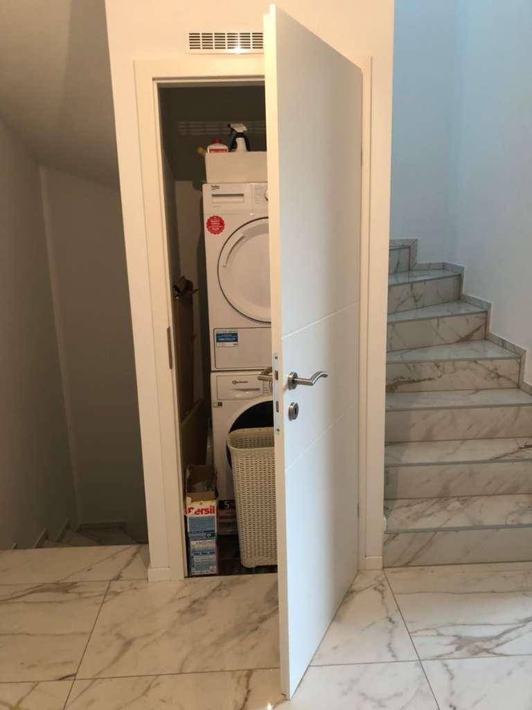 Praktischer Hauswirtschaftsraum mit Waschmaschine und Trockner, geschickt unter der Treppe platziert.