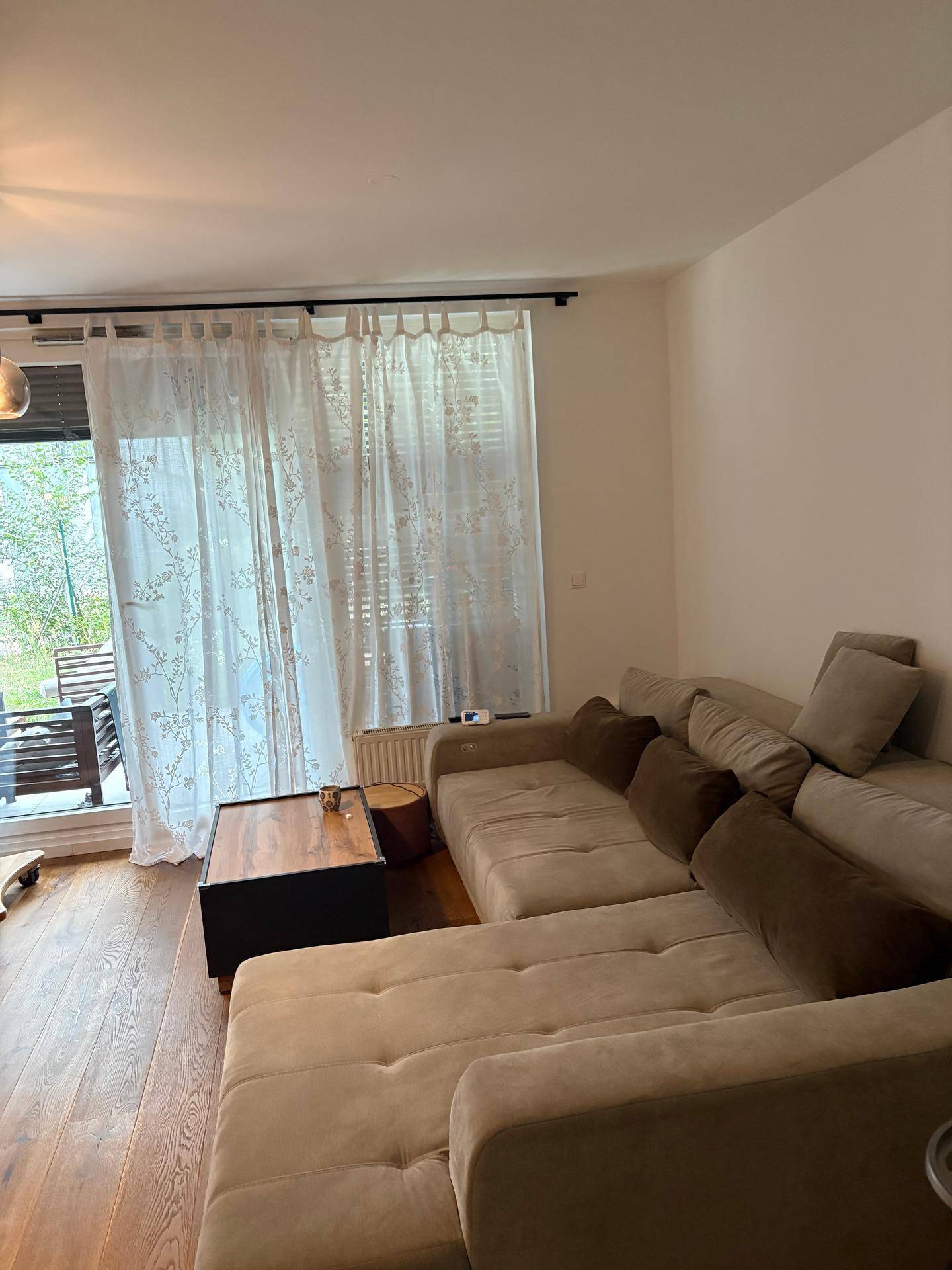 Gemütliches Wohnzimmer mit großem Sofa, Holzboden und Zugang zur Terrasse.
