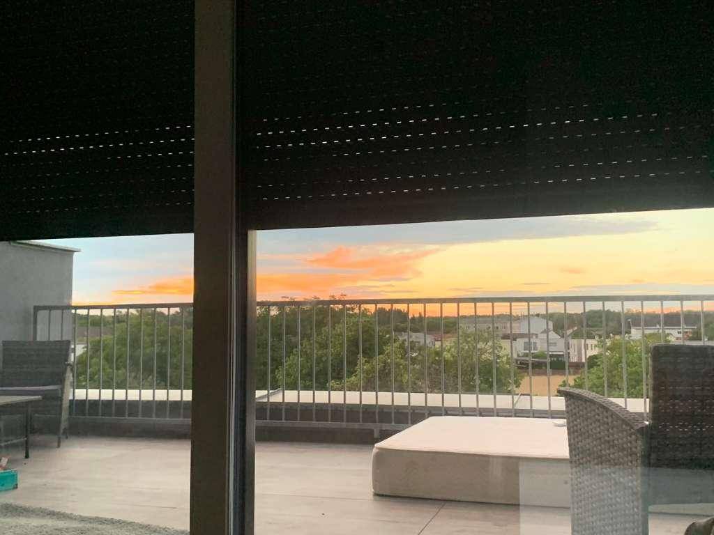 Geräumige Terrasse mit Sitzgelegenheiten und weitem Blick auf den farbenfrohen Sonnenuntergang.