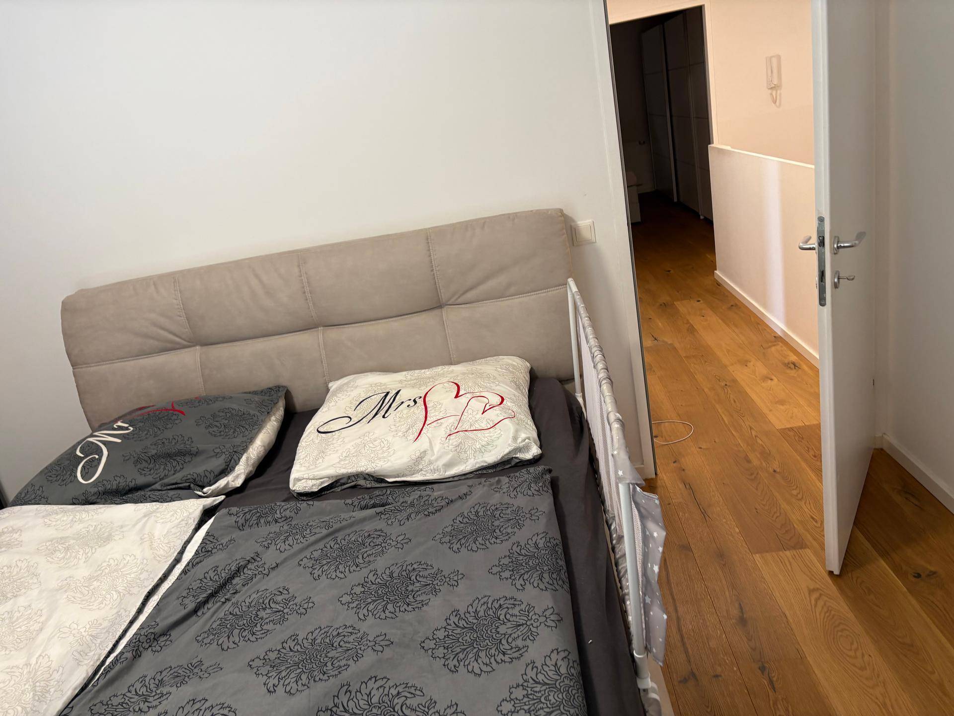Schlafzimmer mit Doppelbett, Holzboden und Zugang zum Flur.