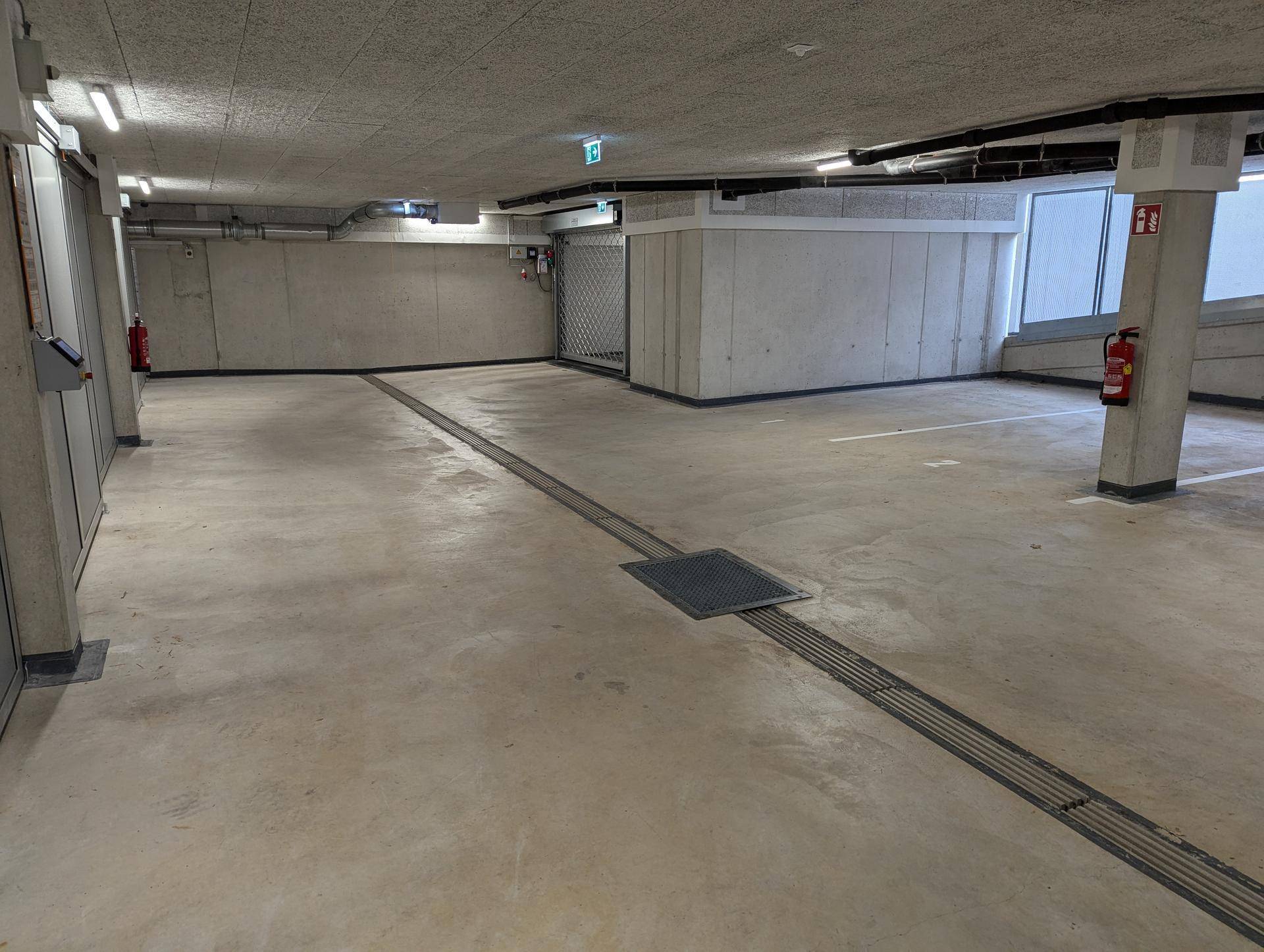 Geräumige Tiefgarage mit Betonwänden und -decken sowie markierten Stellplätzen.