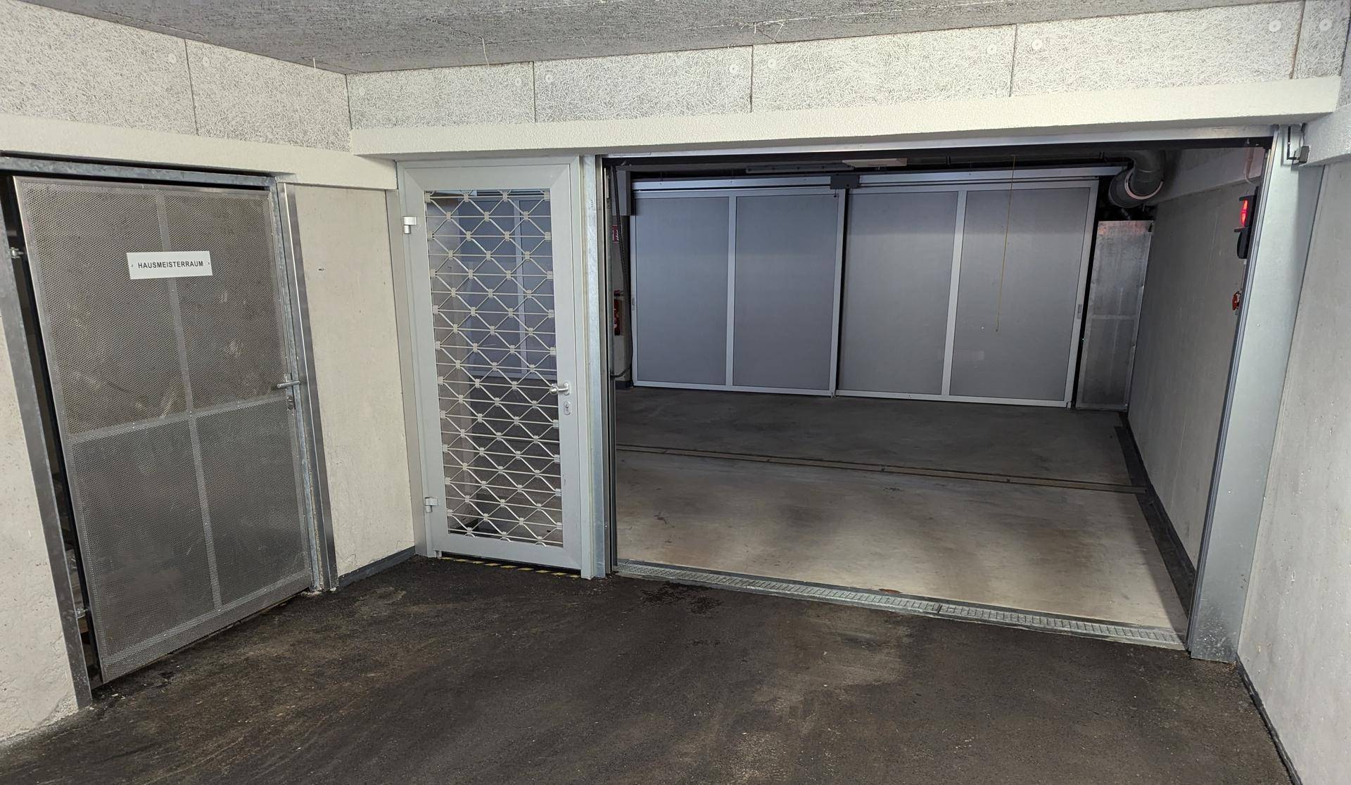 Eingangsbereich einer Tiefgarage mit Zugang zu Lagerräumen und einem automatischen Parksystem.