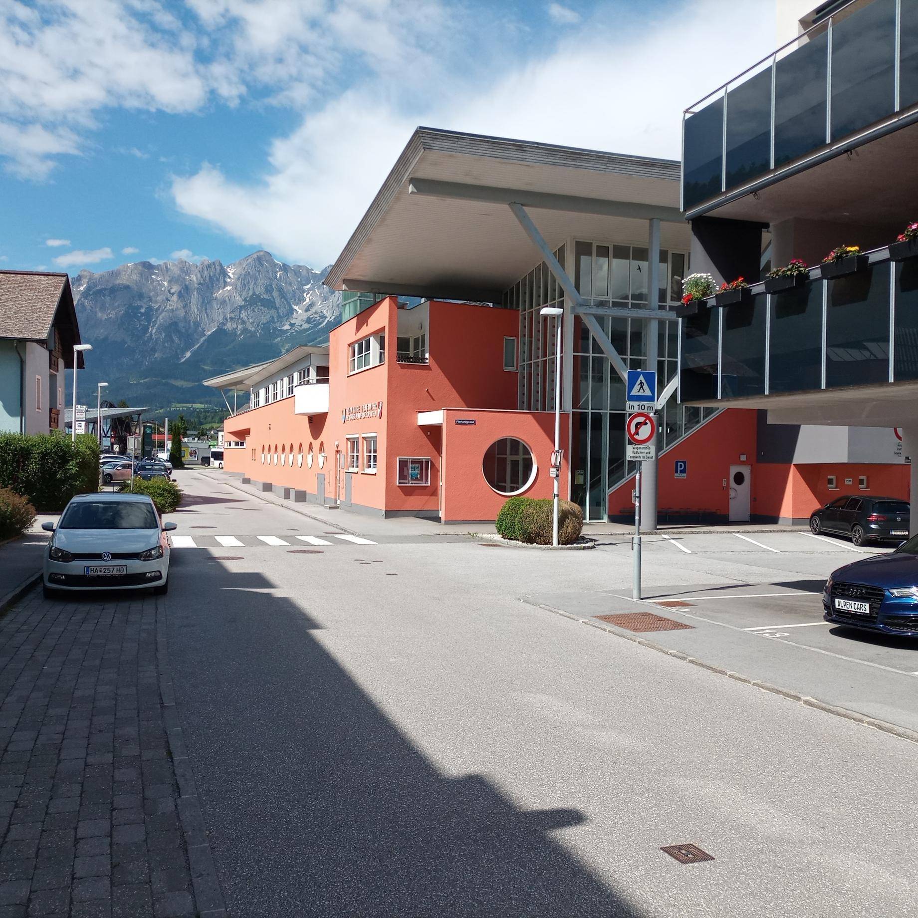Moderne Architektur mit orangefarbener Fassade und Flachdach an einer Straße mit Bergblick.
