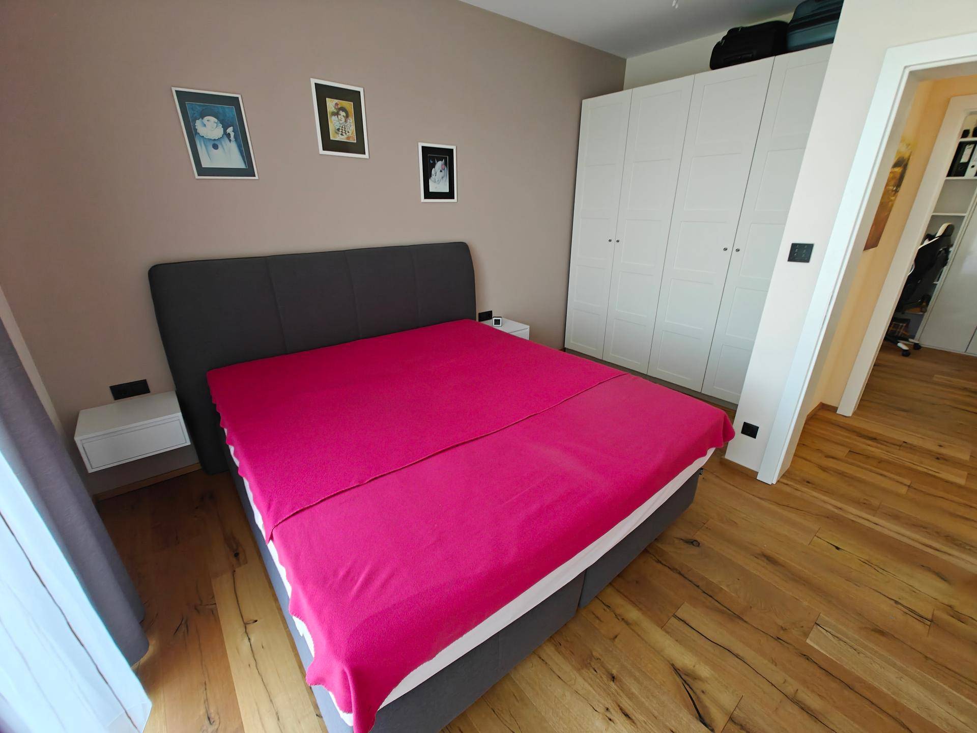 Schlafzimmer mit Doppelbett und einem großen weißen Kleiderschrank.
